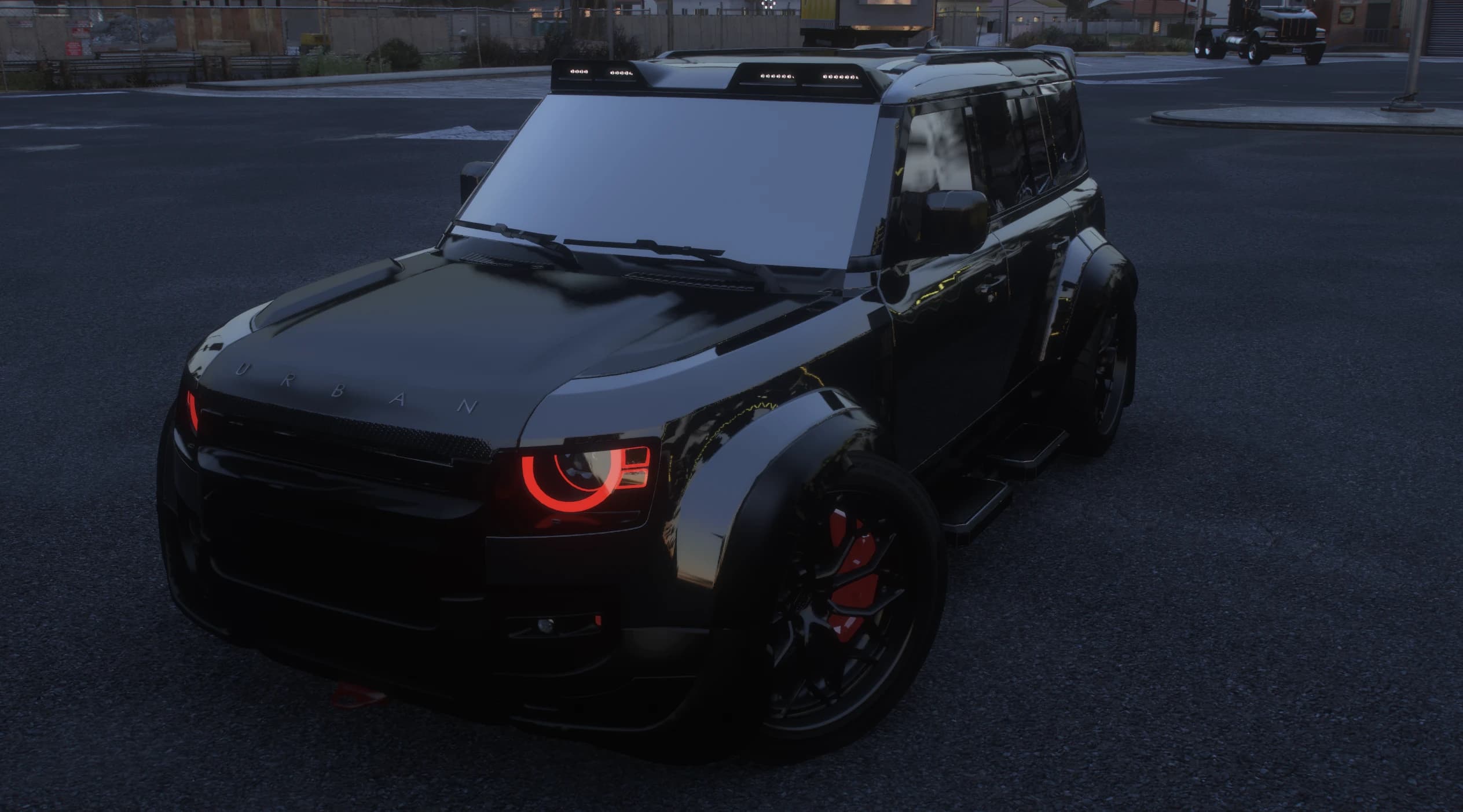 Toma al anochecer del Defender todo negro con las letras URBAN en el capó, halos diurnos brillando en rojo y la visera de techo con módulos LED