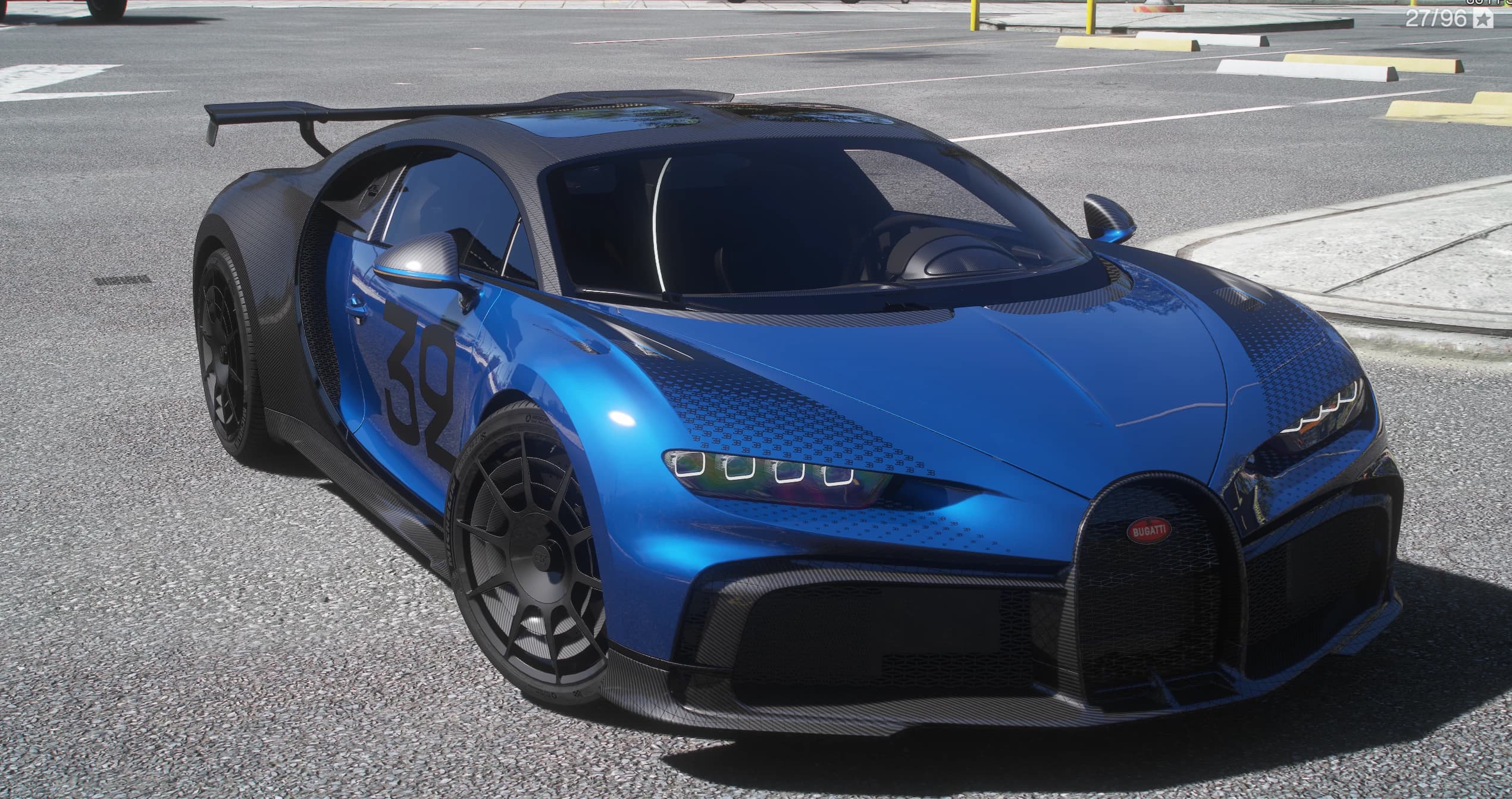 Bugatti Chiron Pur Sport en azul sobre carbono visto, en tres cuartos delantero en una calle de la ciudad, con el número 32 negro en la puerta, el moteado gráfico del capó, la parrilla en herradura y el alerón trasero fijo de carbono