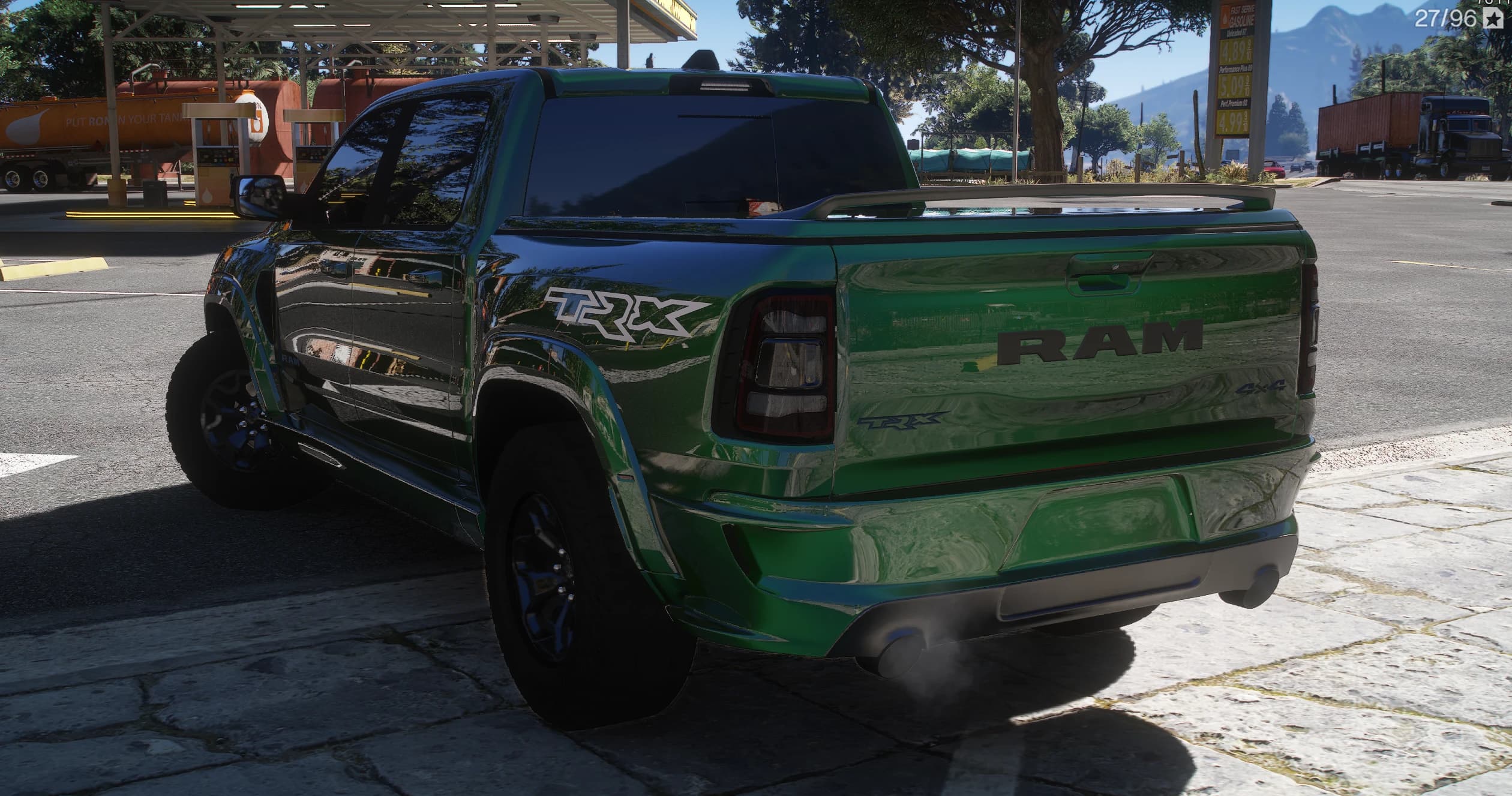 Tres cuartos trasero de la TRX verde parada en una gasolinera Fast Serve, con el rótulo RAM en el portón, el emblema 4x4, la cubierta de la caja y el humo del escape bajo el paragolpes