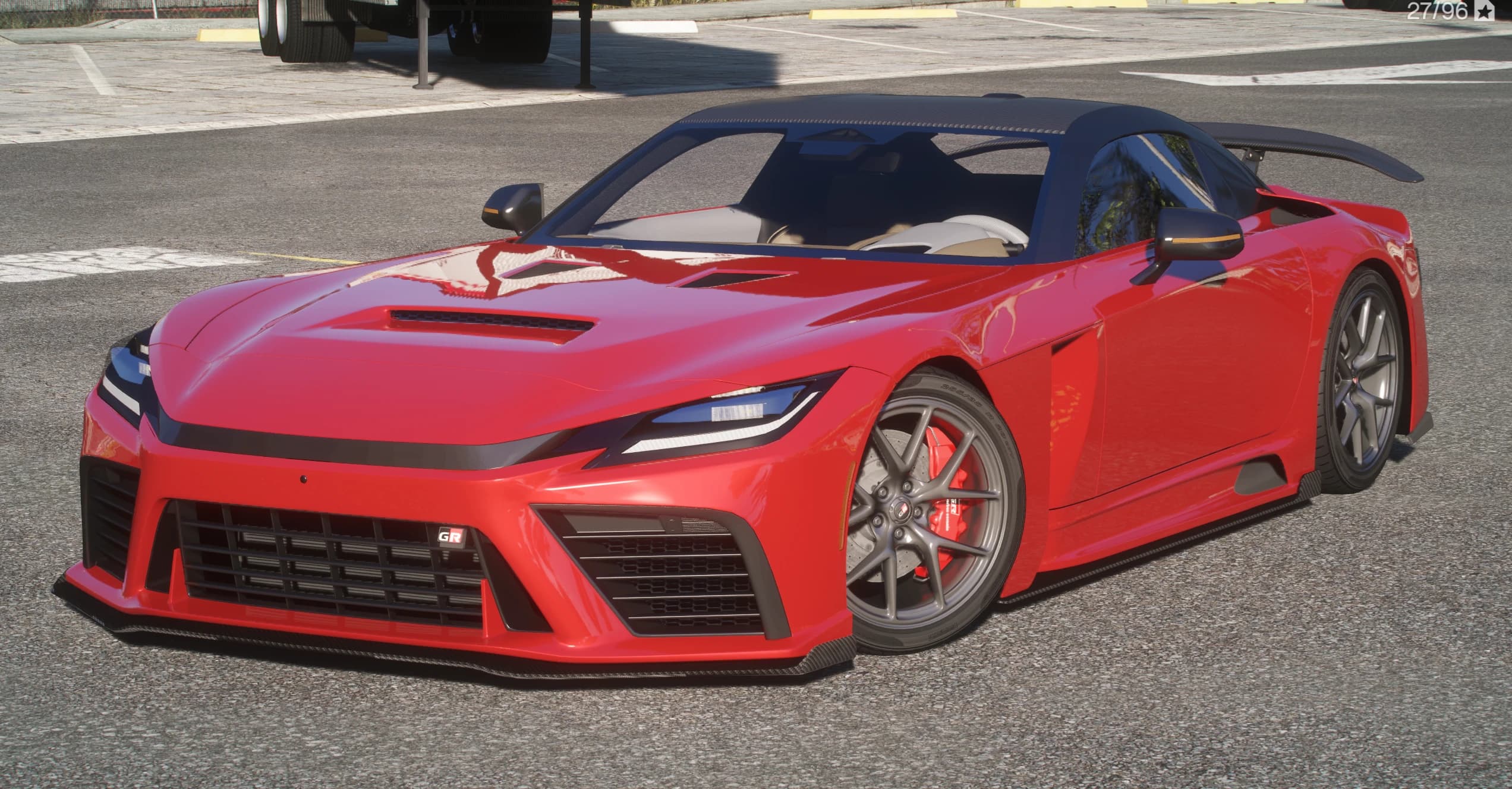 Cupé deportivo Toyota GR GT rojo con techo de carbono, gran alerón trasero y llantas grises de varios radios con pinzas rojas, tres cuartos frontal en un aparcamiento