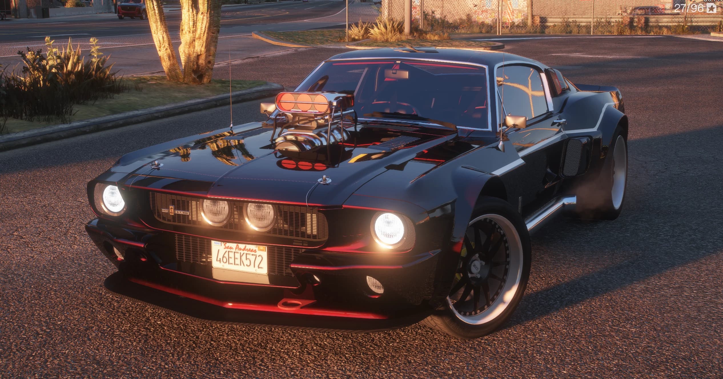 Shelby Mustang GT500 1967 en negro con filetes rojos, tres cuartos delantero al atardecer, compresor cromado asomando por el capó, los cuatro faros redondos encendidos y matrícula de San Andreas 46EEK572