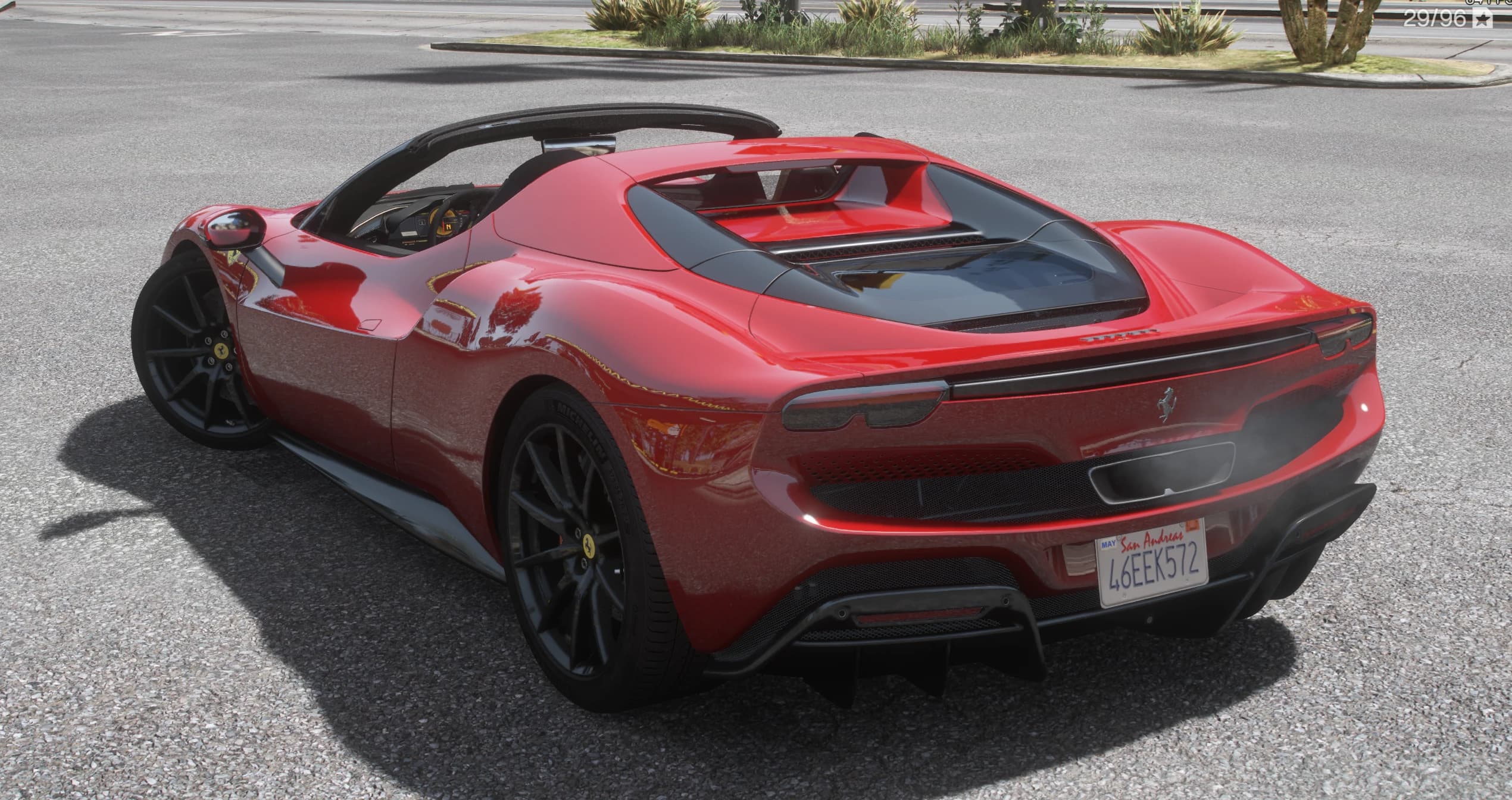 Tres cuartos trasero del 296 GTS rojo con el techo guardado, mostrando el capó de cristal del motor, los pilotos redondos gemelos y el difusor negro