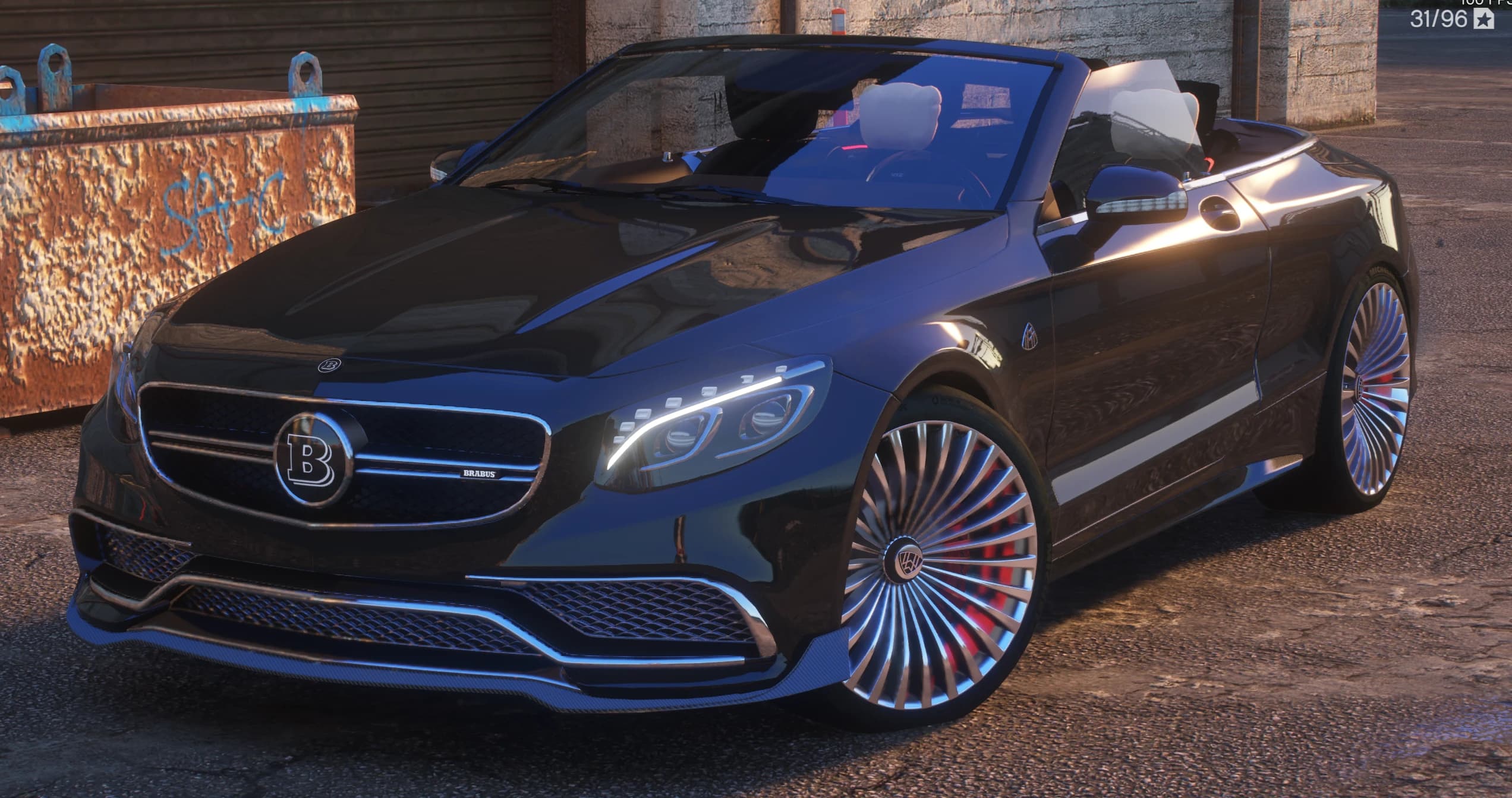 Vista frontal en tres cuartos del Maybach S650 Cabriolet negro descapotado, con la insignia Brabus en la parrilla y llantas cromadas de estilo turbina sobre pinzas rojas, aparcado junto a un contenedor oxidado