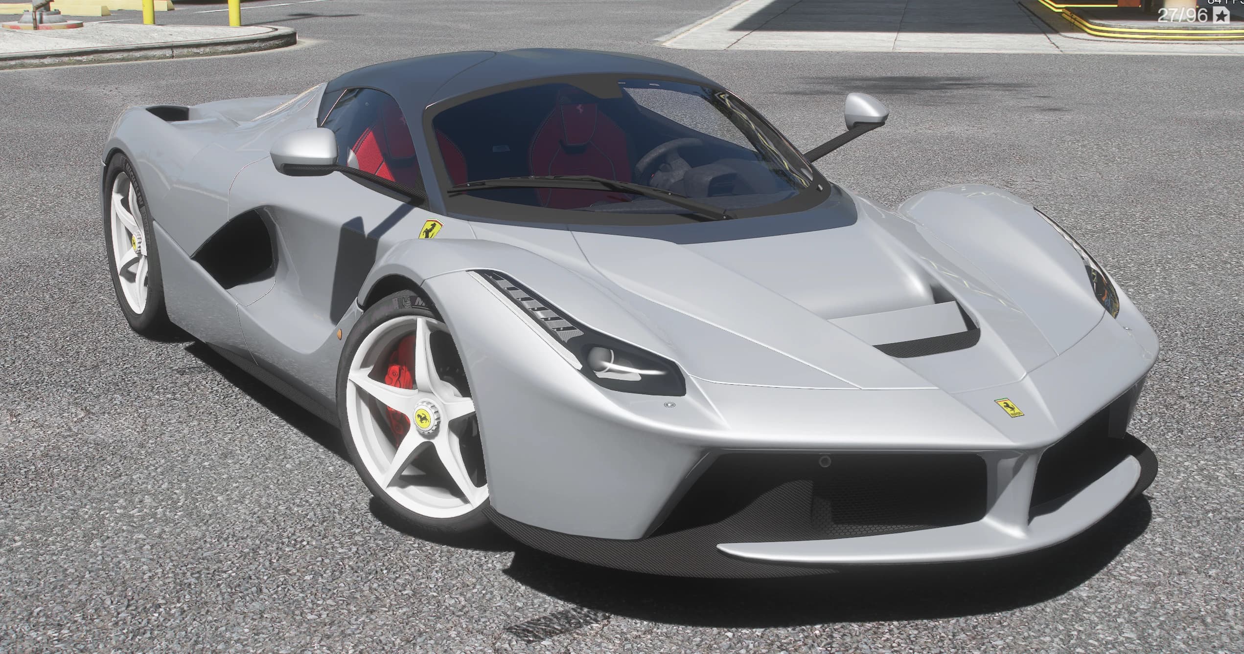 Ferrari LaFerrari plateado en tres cuartos delantero en una calle de la ciudad, con el habitáculo rojo visible a través de los cristales, llantas blancas de cinco radios y pinzas de freno rojas