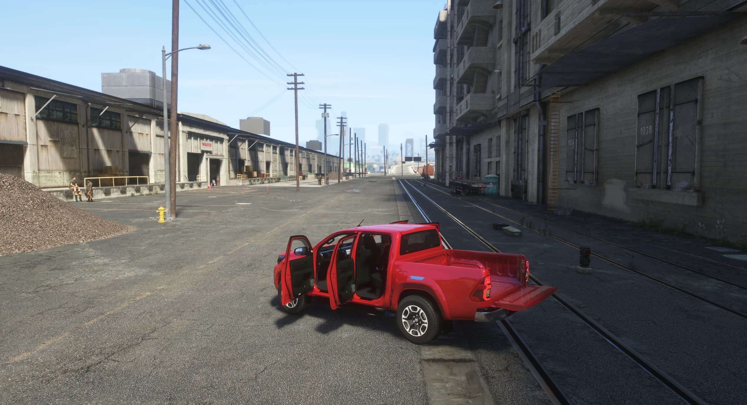 El Hilux rojo aparcado en una calle del puerto con las cuatro puertas abiertas y el portón bajado, enseñando el habitáculo oscuro