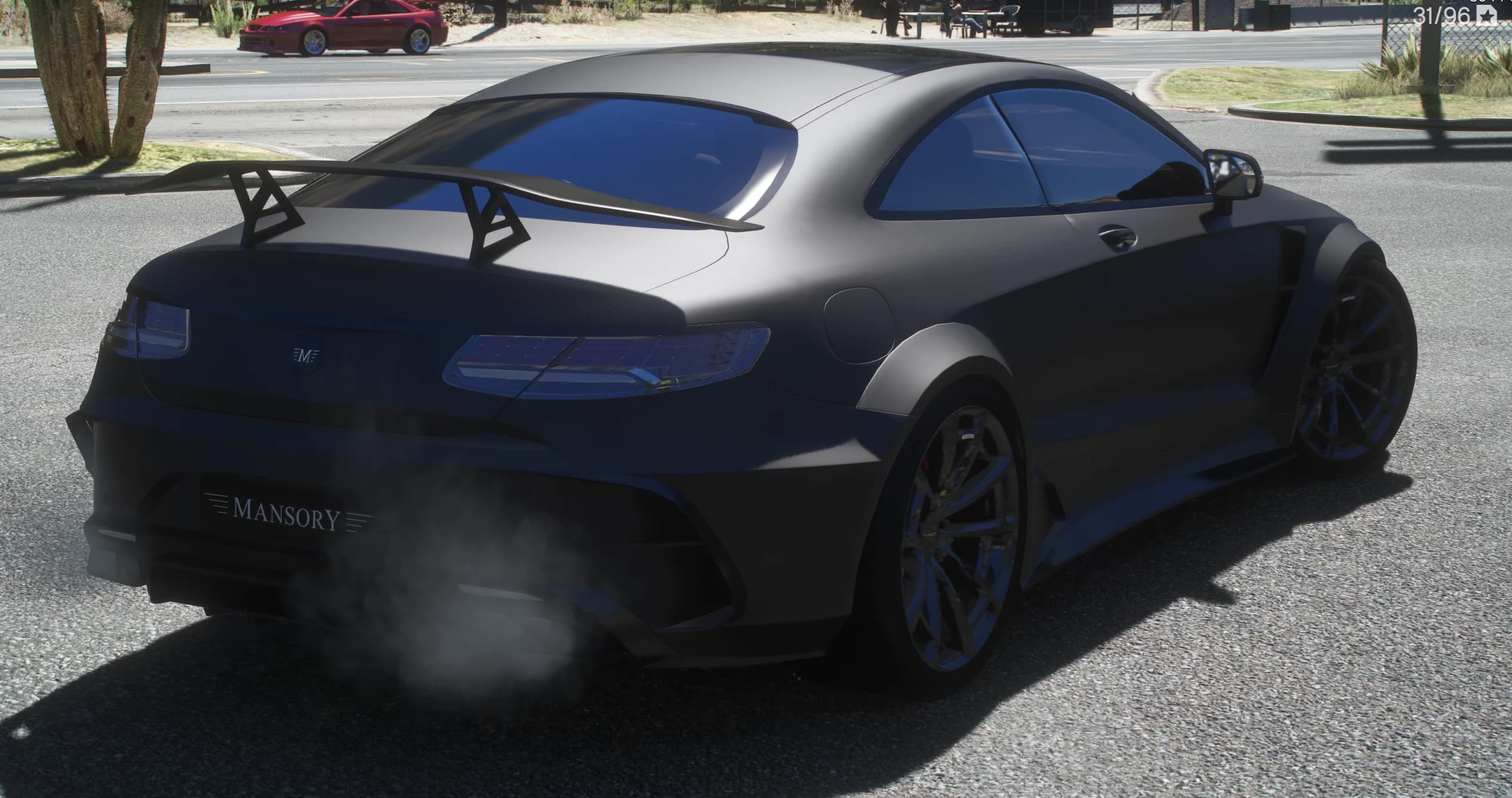 Vista trasera en tres cuartos a la sombra con el alerón GT alto de soportes angulosos, el marco MANSORY en el paragolpes y el humo del escape saliendo del difusor