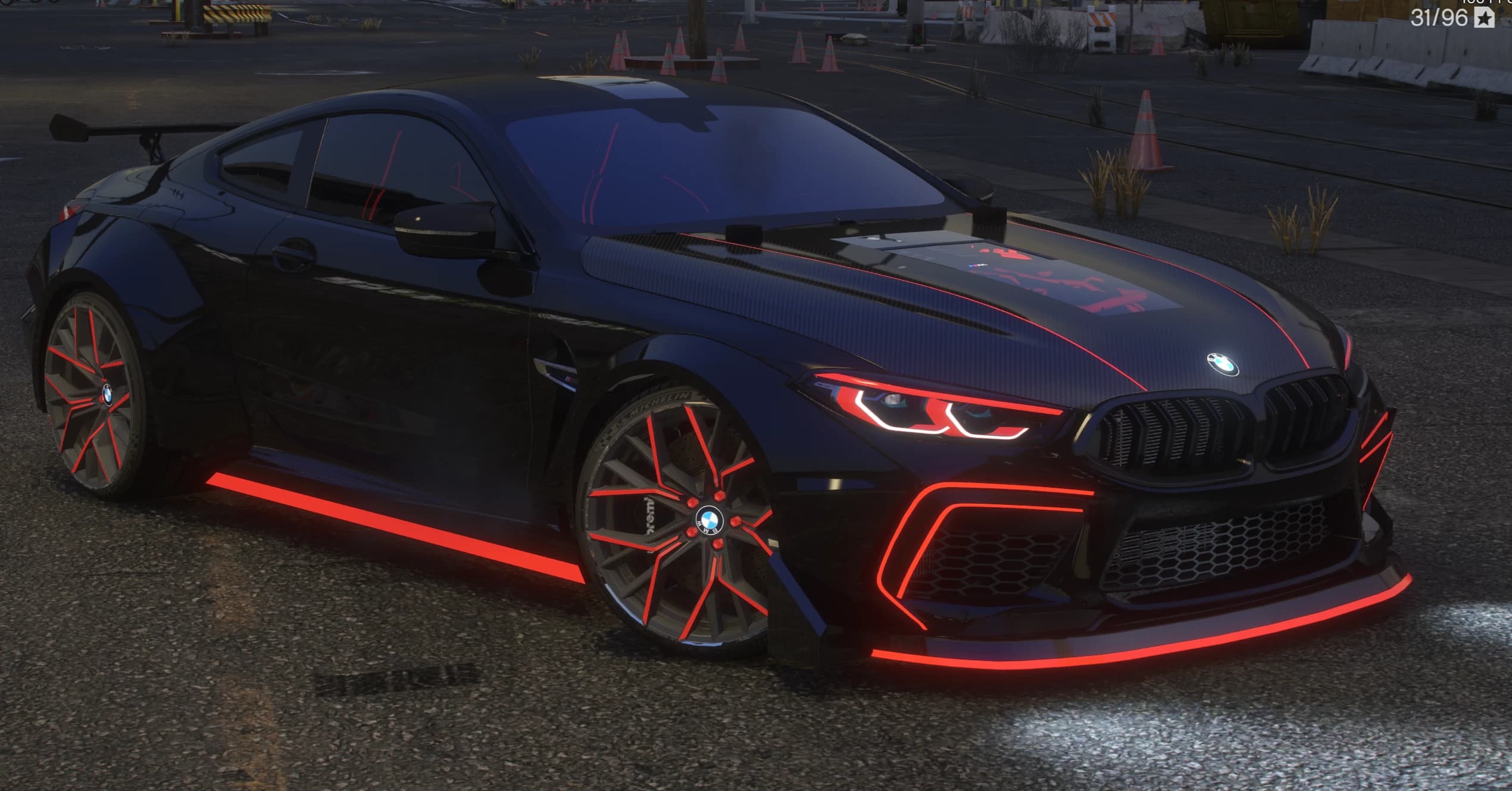 Toma nocturna del M8 negro con las tiras de luz roja encendidas en taloneras y splitter, faros iluminados en rojo y el panel transparente del capó
