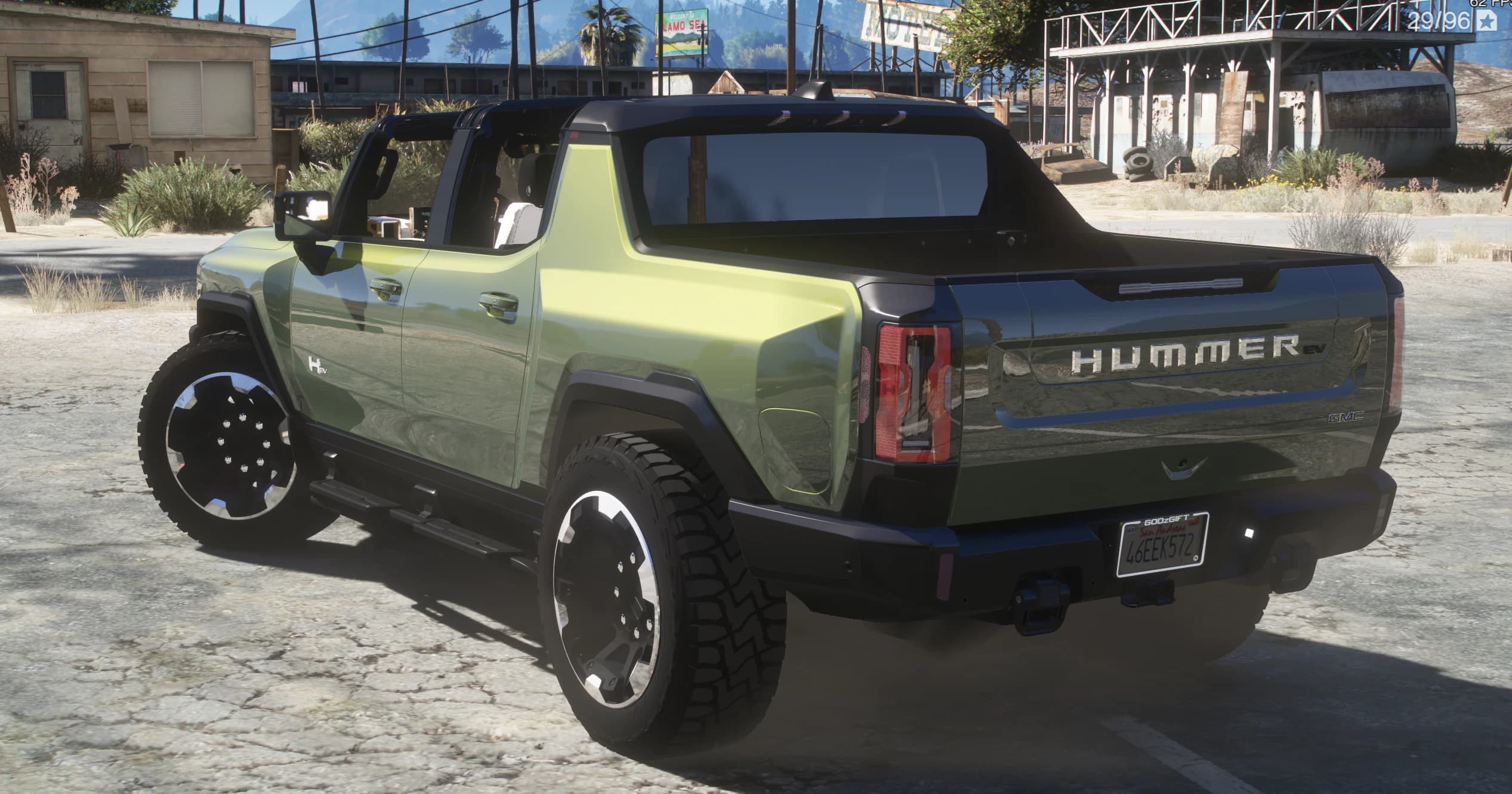 Tres cuartos trasero con el rótulo HUMMER EV en el portón y matrícula de San Andreas, en una zona de moteles del desierto