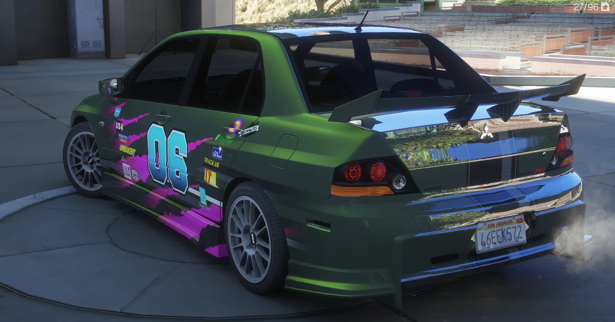 Tres cuartos trasero del Evo VIII verde con el alerón alto de carbono, la insignia Evolution MR del maletero y humo saliendo del escape, con el vinilo del número 06 recorriendo el lateral