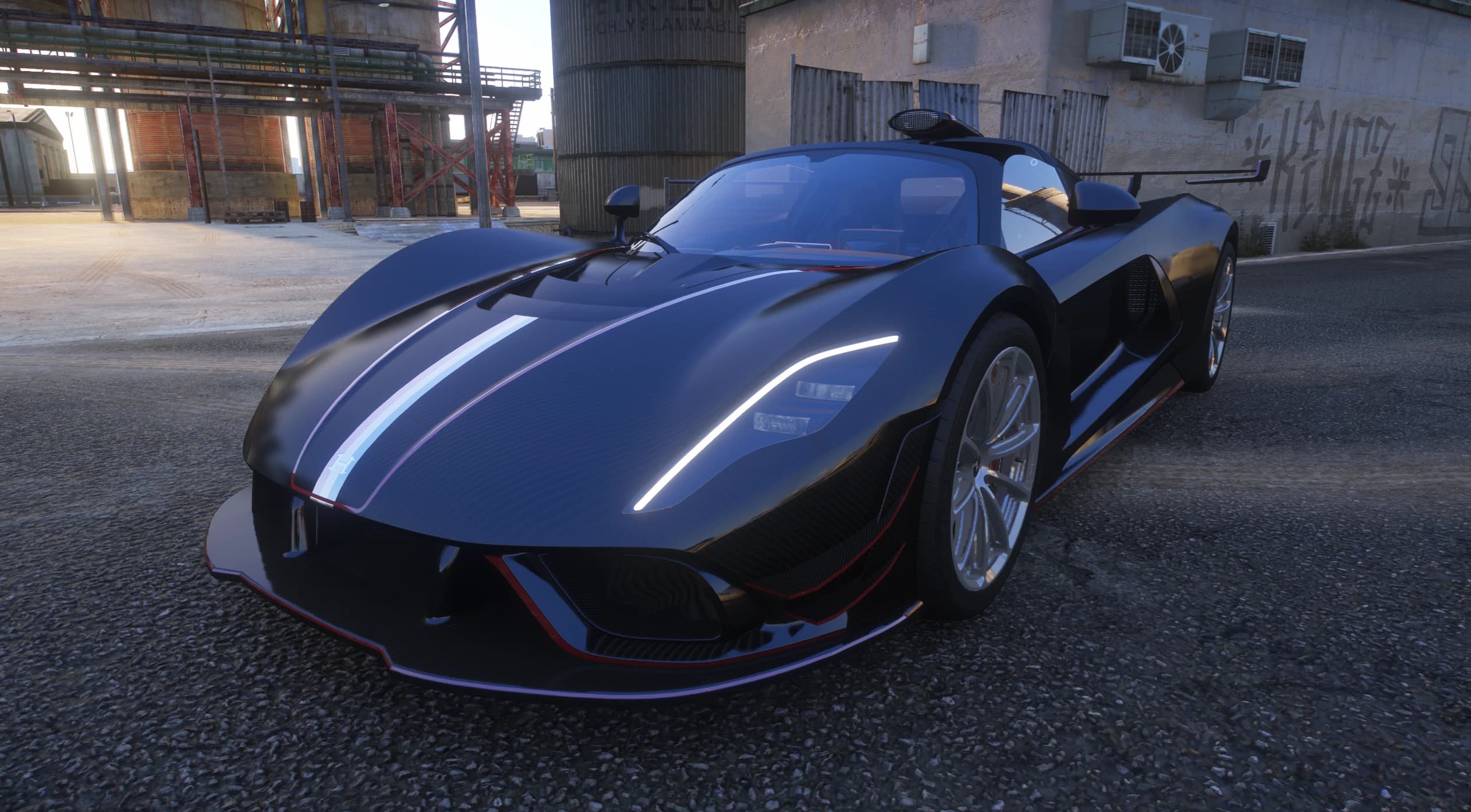 El Venom F5 Roadster en acabado de carbono negro con una franja blanca, tres cuartos frontal junto a un edificio industrial