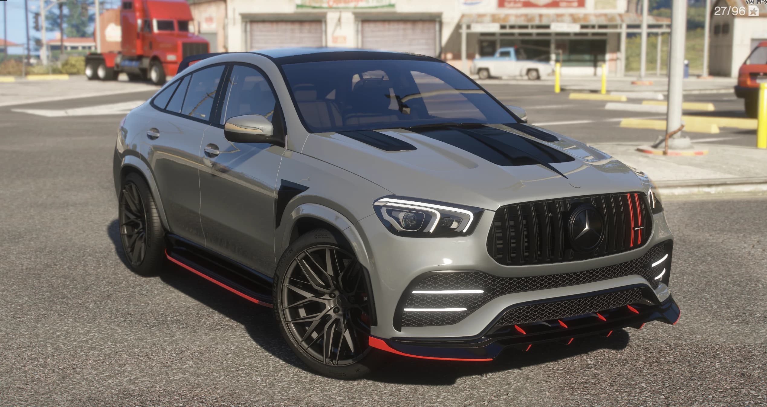 Mercedes-Benz GLE 53 AMG coupé en gris con el kit Larte Design, en tres cuartos delantero frente a un taller de carretera, con los remates rojos del labio delantero y las taloneras, la parrilla AMG de lamas verticales y las llantas multirradio negras