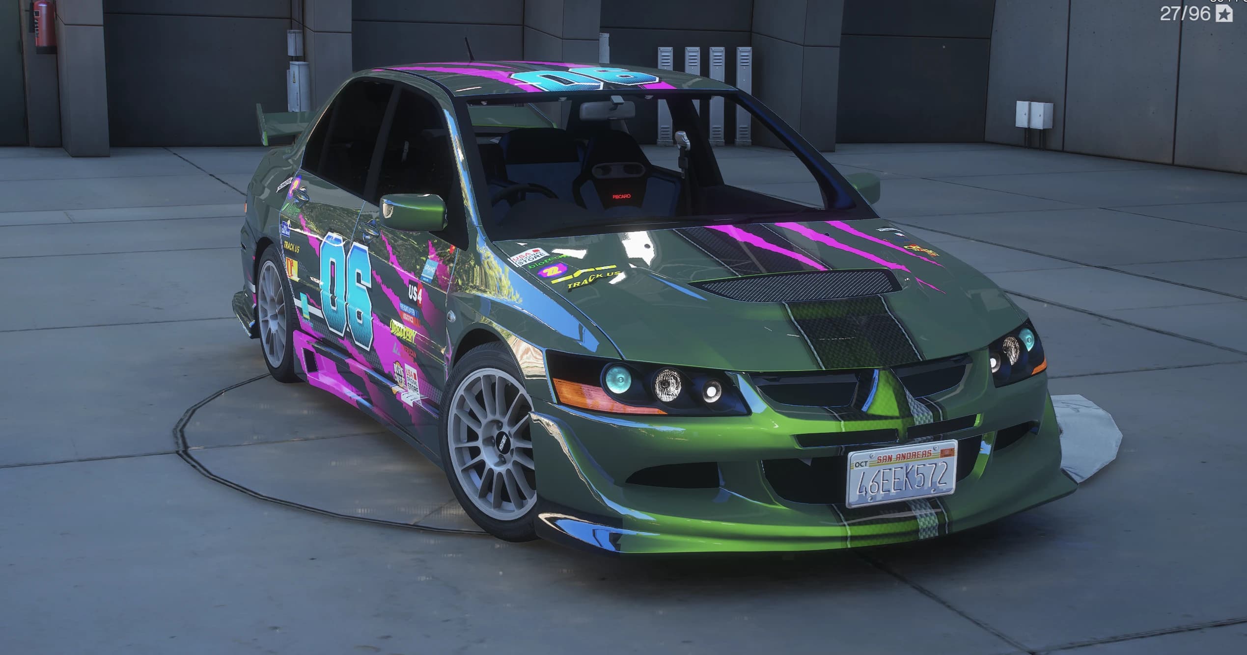 Lancer Evolution VIII 2003 verde en tres cuartos delantero sobre una plataforma giratoria de hormigón, con vinilo de carreras del número 06 en rosa y cian, llantas multirradio blancas y matrícula de San Andreas