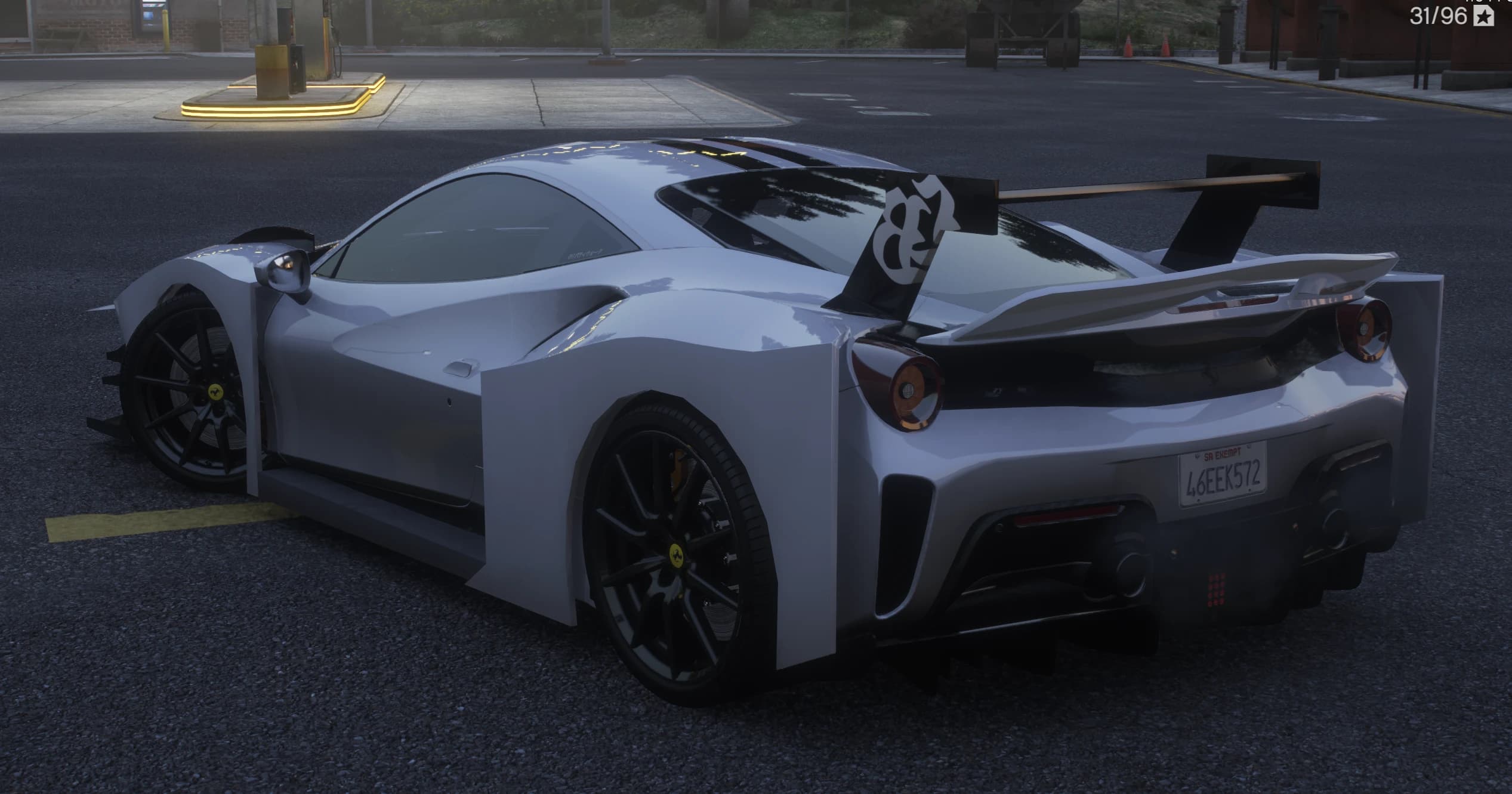 Vista trasera en tres cuartos junto a una gasolinera con el alerón GT anclado al chasis con el emblema LB, pilotos redondos, aletas traseras cuadradas y matrícula de San Andreas