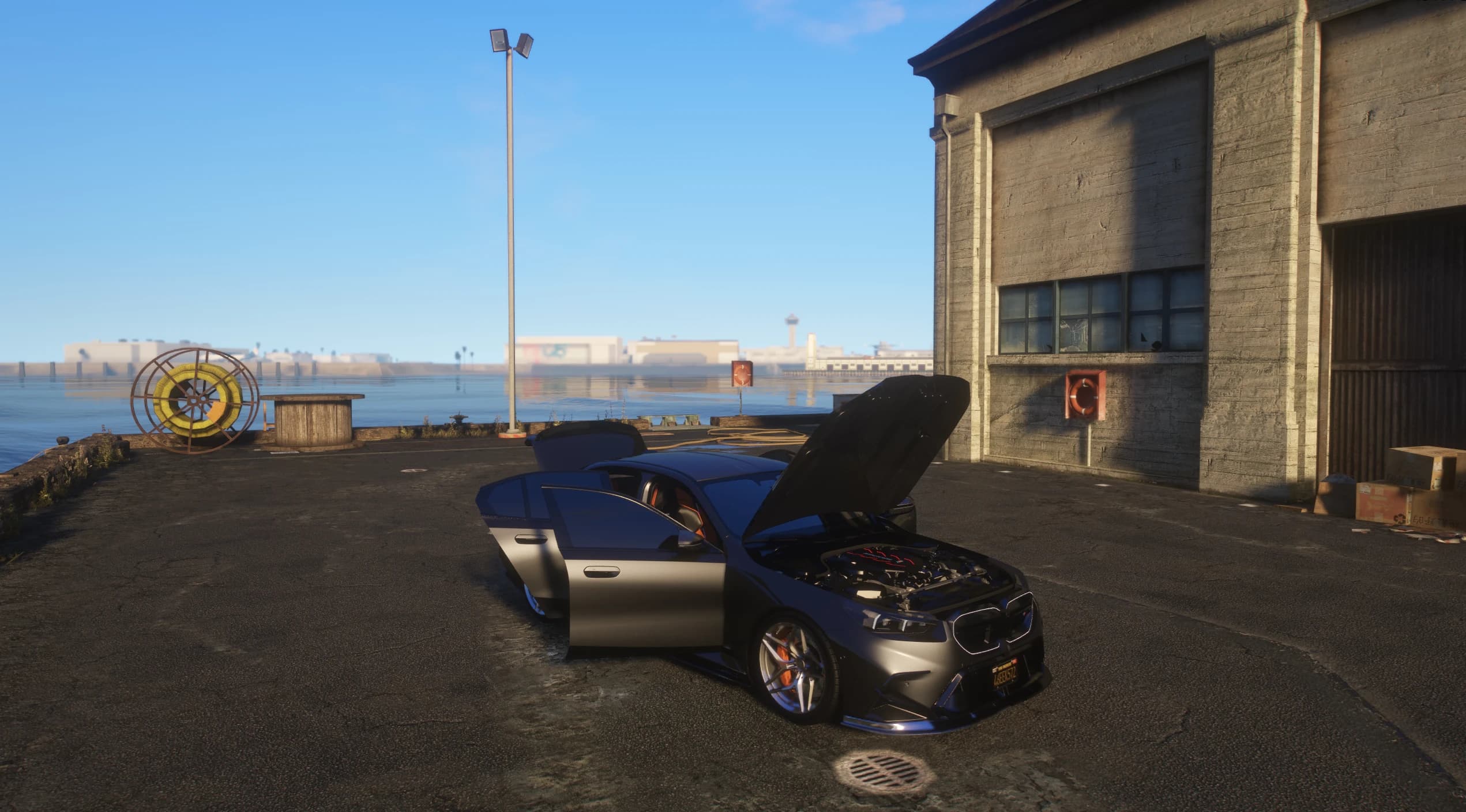 El M5 aparcado en un muelle con las puertas y el capó abiertos, enseñando el vano motor completamente modelado y el interior con detalles naranjas