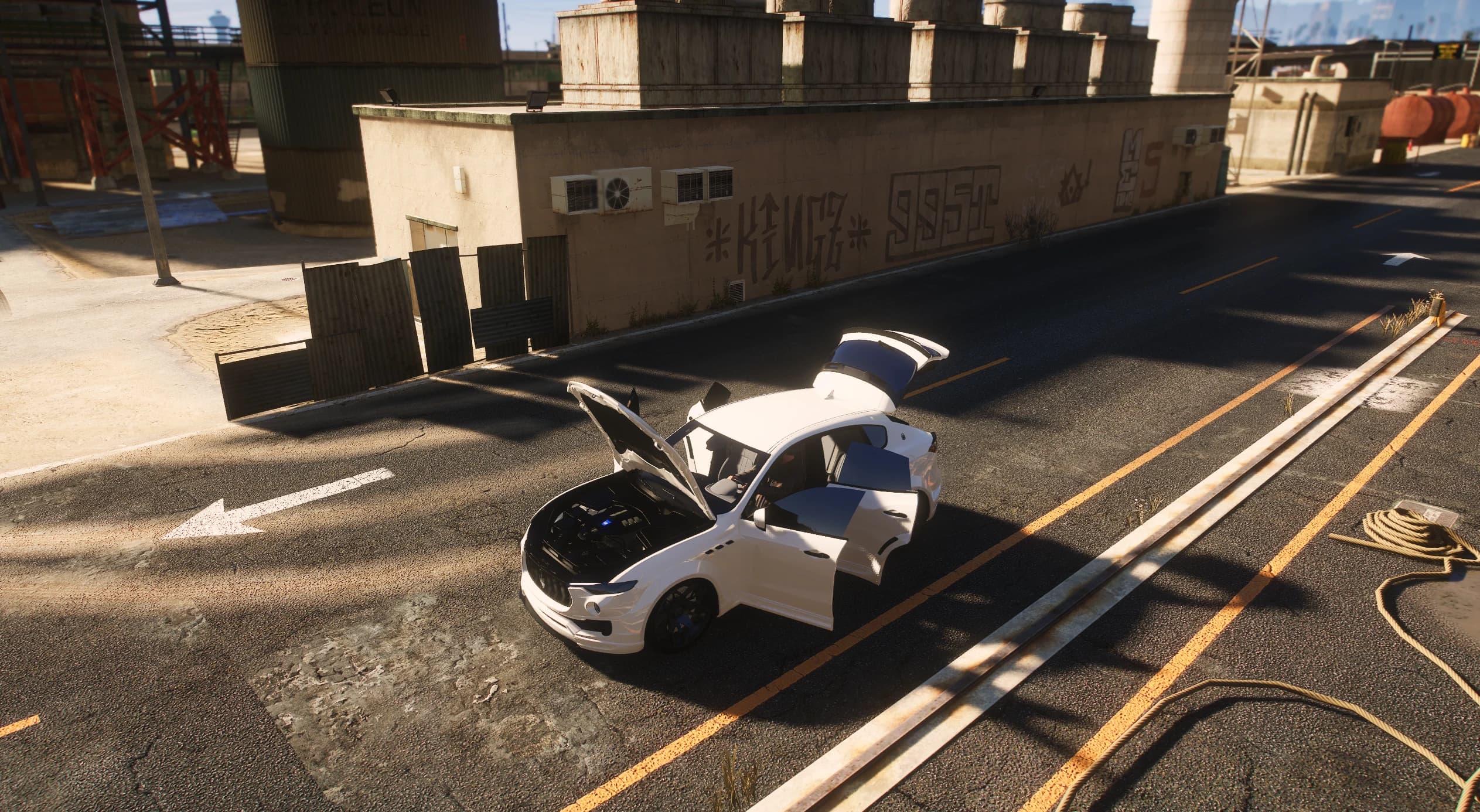 Plano elevado del Levante blanco en una calle del puerto con el capó, las cuatro puertas y el portón trasero abiertos, dejando ver el vano motor modelado y el interior de cuero claro