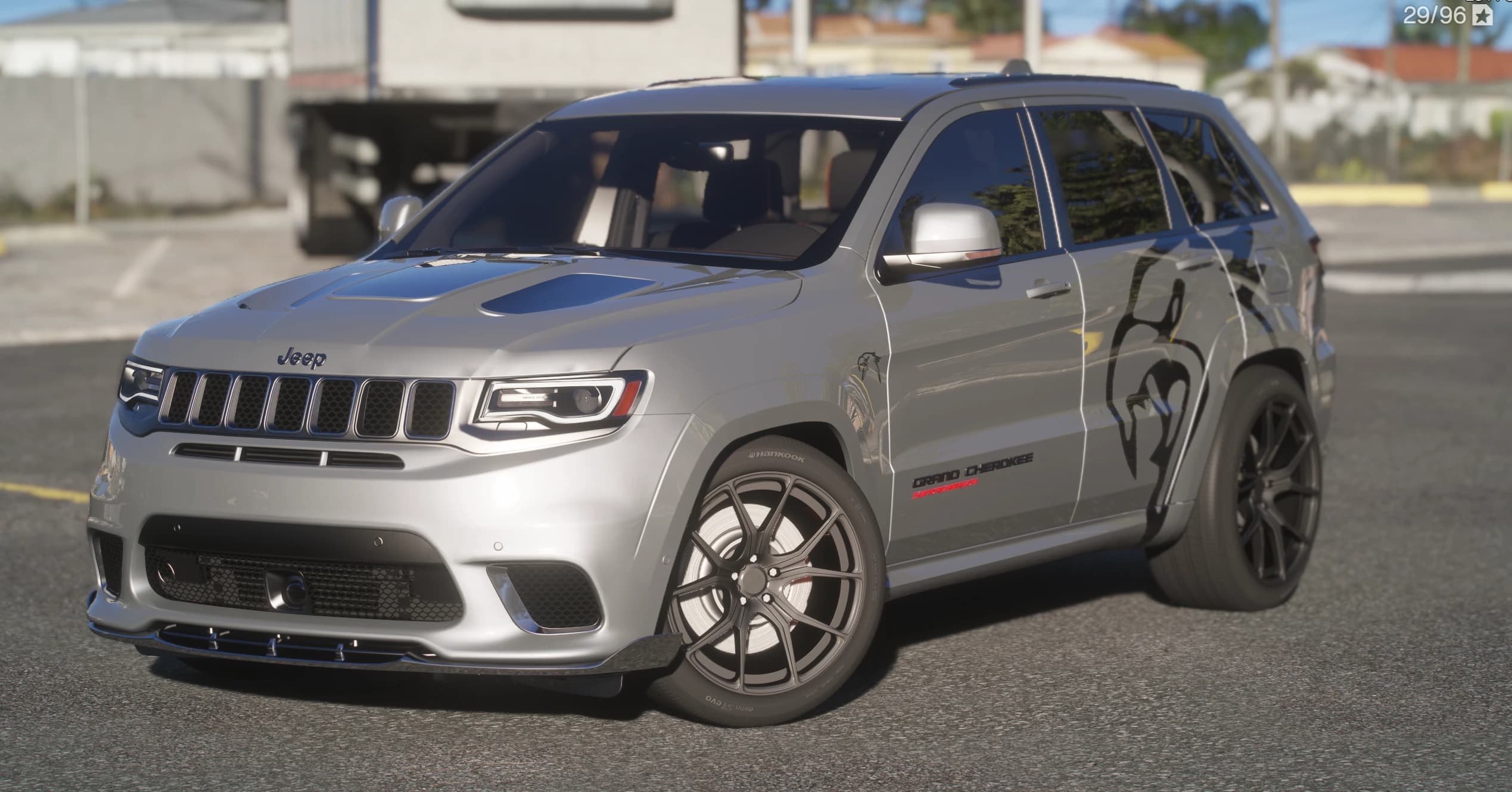Jeep Grand Cherokee Trackhawk en plata, tres cuartos frontal con la toma en el capó, la insignia Grand Cherokee Supercharged, llantas negras y un gráfico de león negro en el cuarto trasero