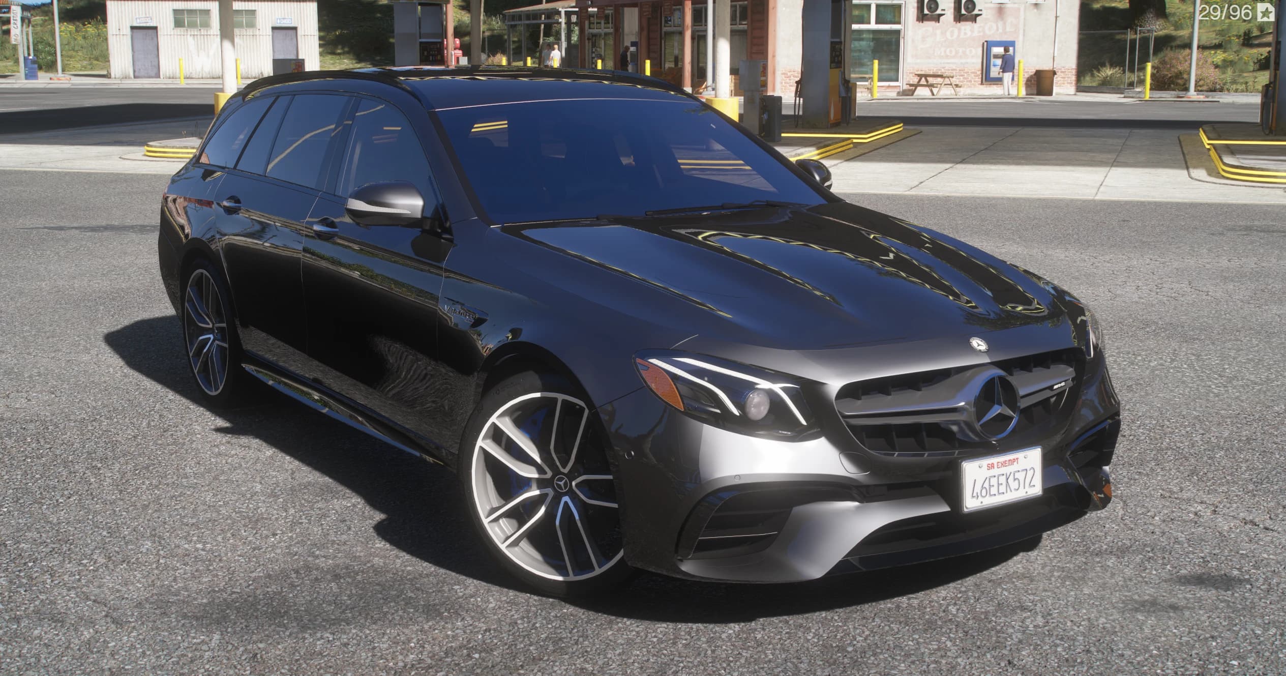Mercedes-AMG E63 S W213 Estate en negro, tres cuartos frontal con la parrilla Panamericana, la insignia V8 Biturbo en la aleta y llantas AMG multirradio con pinzas azules, en una gasolinera