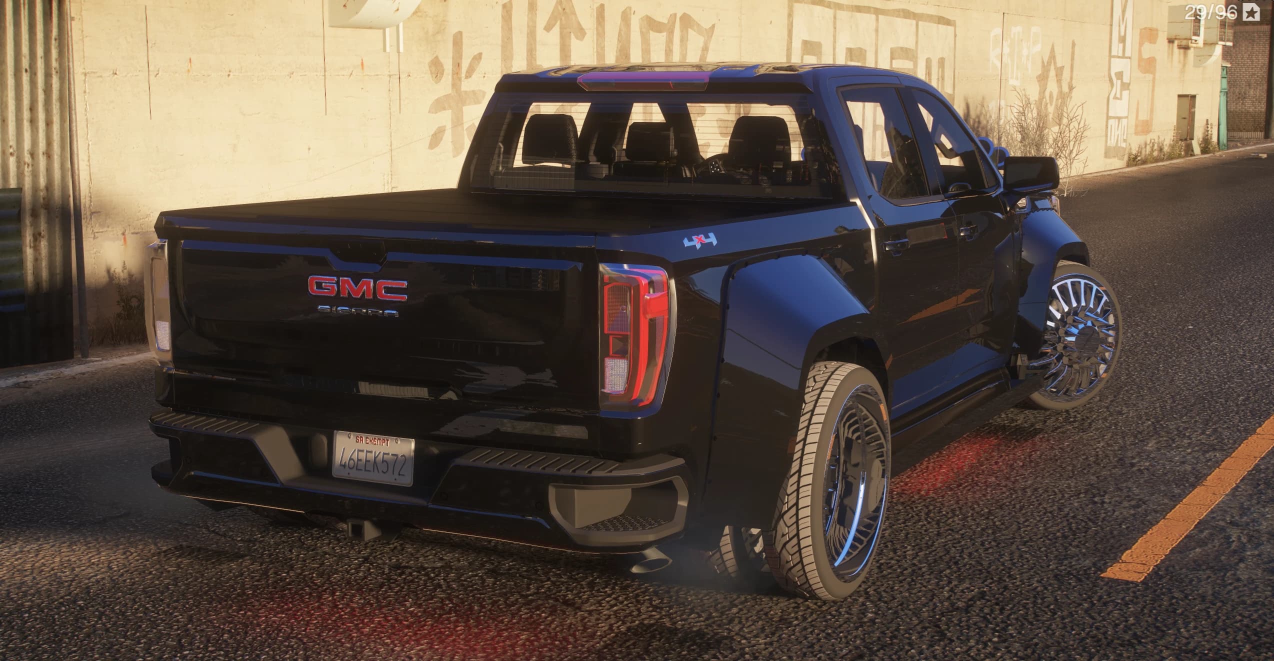 Tres cuartos trasero del Sierra con la insignia GMC Sierra en el portón, el rótulo 4x4, una tapa de caja y llantas dually cromadas