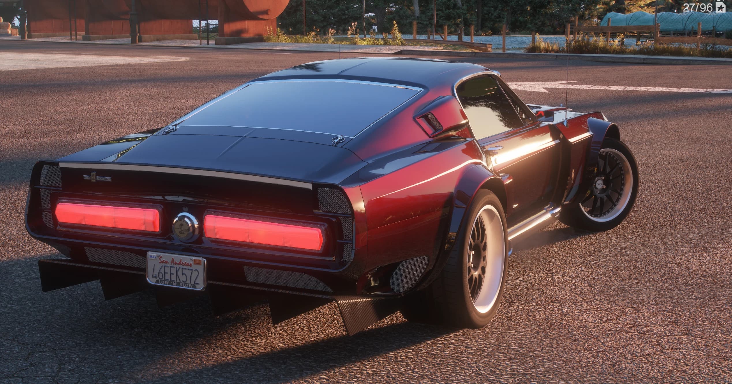 Tres cuartos trasero del Shelby con los pasos de rueda traseros en rojo caramelo, los dos pilotos rojos de lado a lado con el emblema de la cobra Shelby en medio, un difusor trasero con aletas y llantas de labio blanco bajo aletines anchos