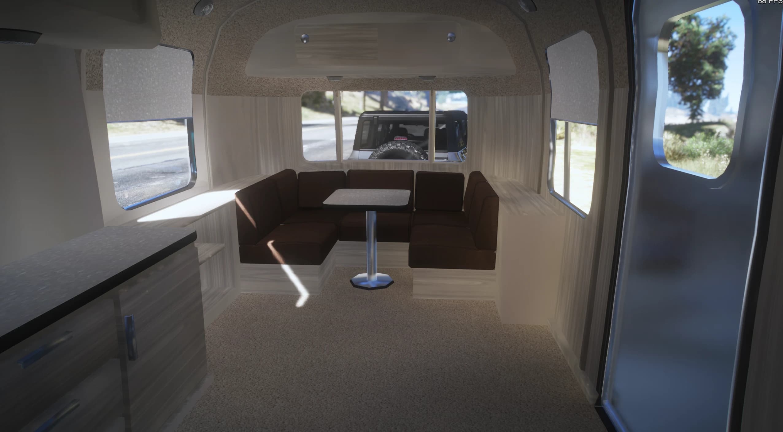 Interior modelado de la White Liner con un banco comedor envolvente marrón alrededor de una mesa de pie, encimera de cocina y ventanas con cortinas