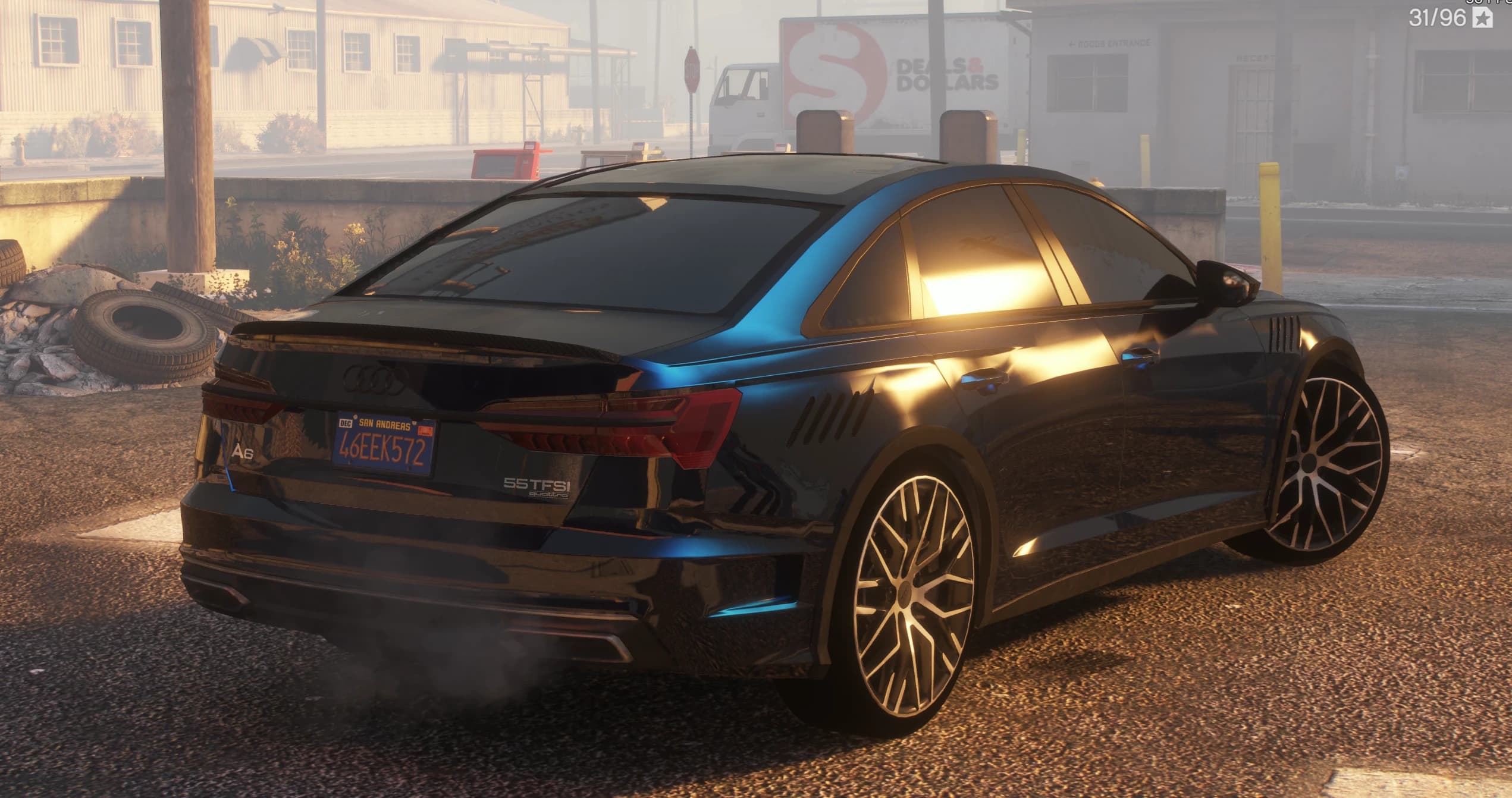 Vista trasera en tres cuartos al atardecer con las insignias A6 y 55 TFSI quattro, el alerón de carbono en el maletero y las salidas laterales tras las ruedas delanteras