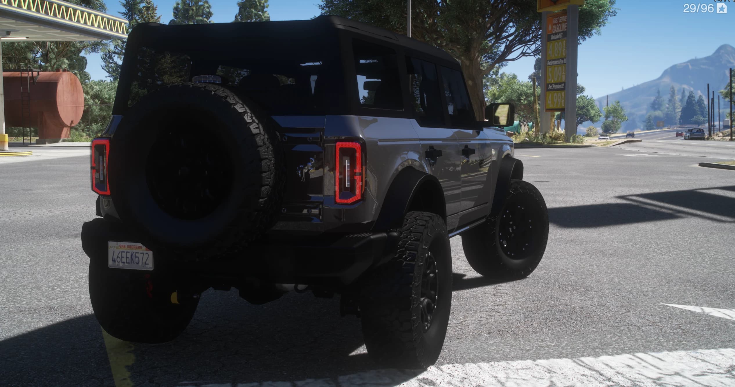 Tres cuartos trasero del Bronco gris con la rueda de repuesto en el portón y los pilotos BRONCO en una gasolinera