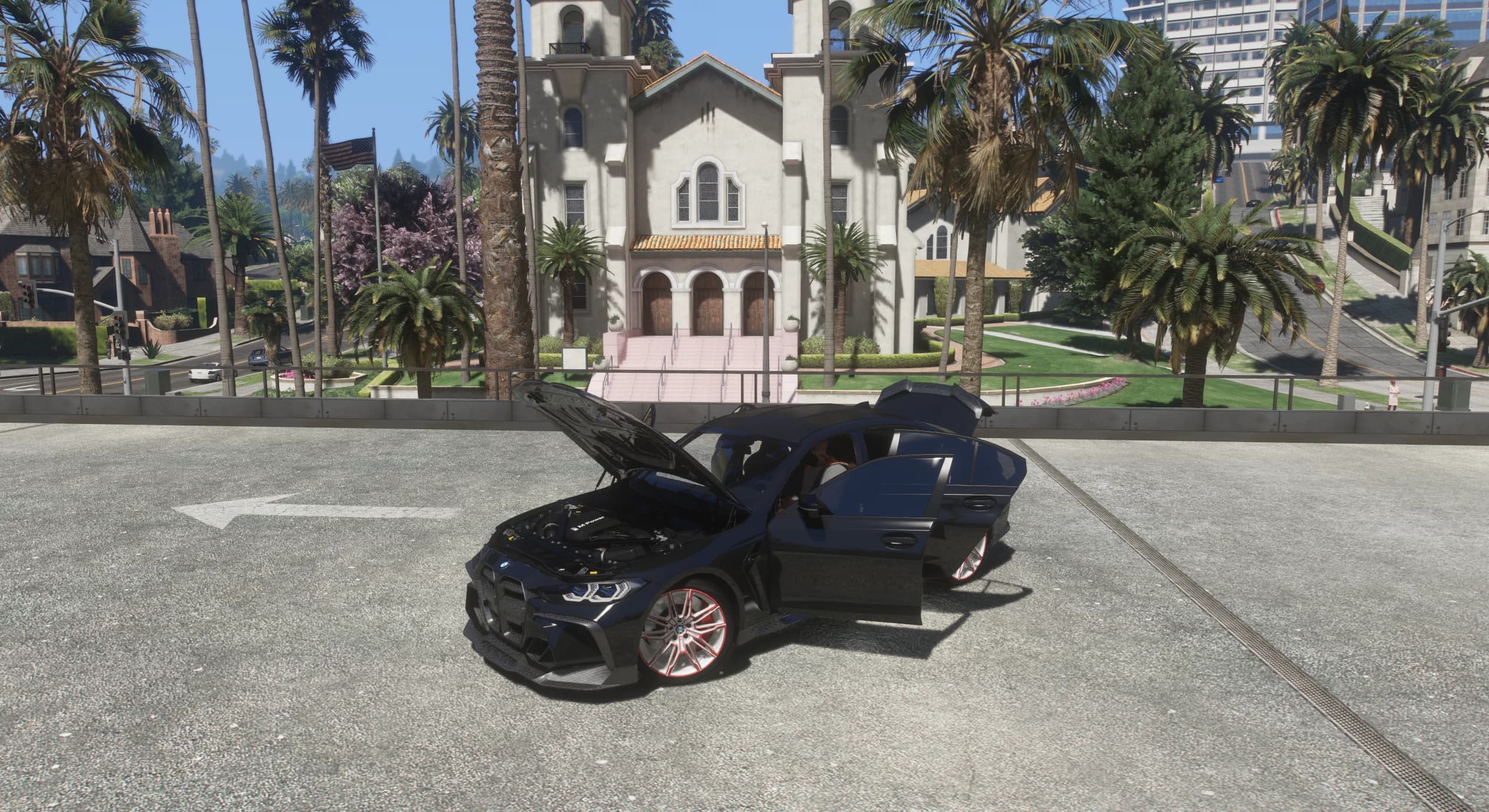 Vista lateral del M3 con el capó, ambas puertas y el maletero abiertos, dejando ver el detallado vano motor M Power frente a una iglesia de Vinewood