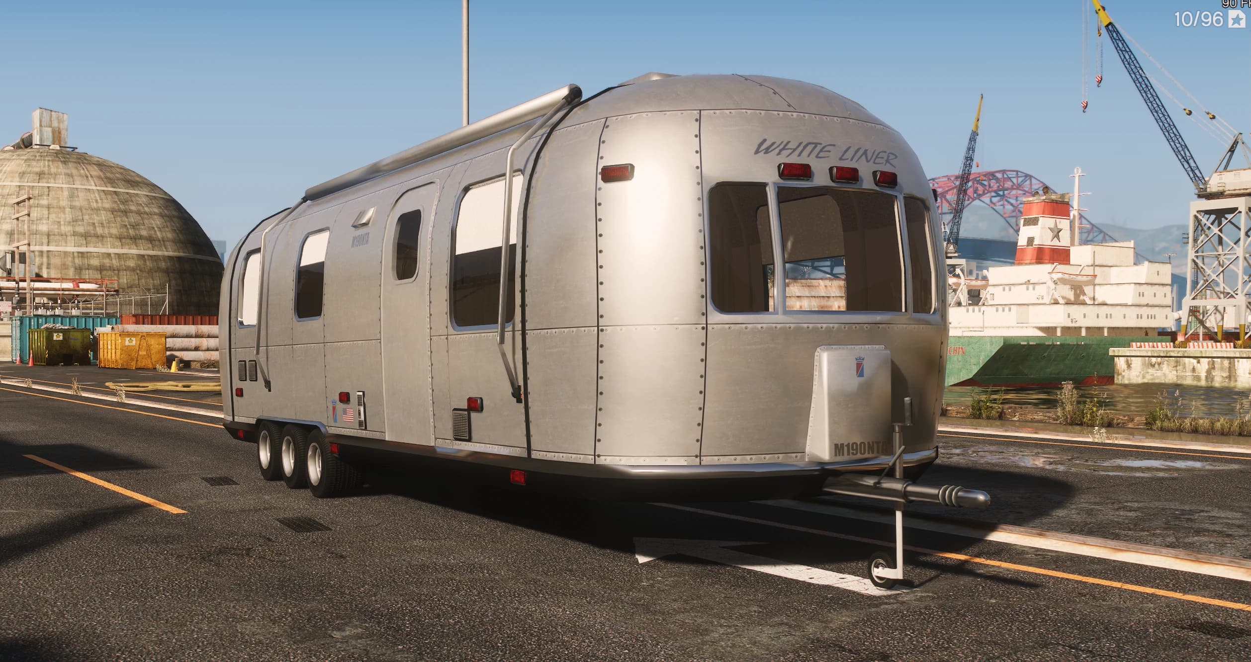Caravana de viaje Albany White Liner de aluminio remachado plateado con el rótulo WHITE LINER y chasis de tres ejes, aparcada en los muelles