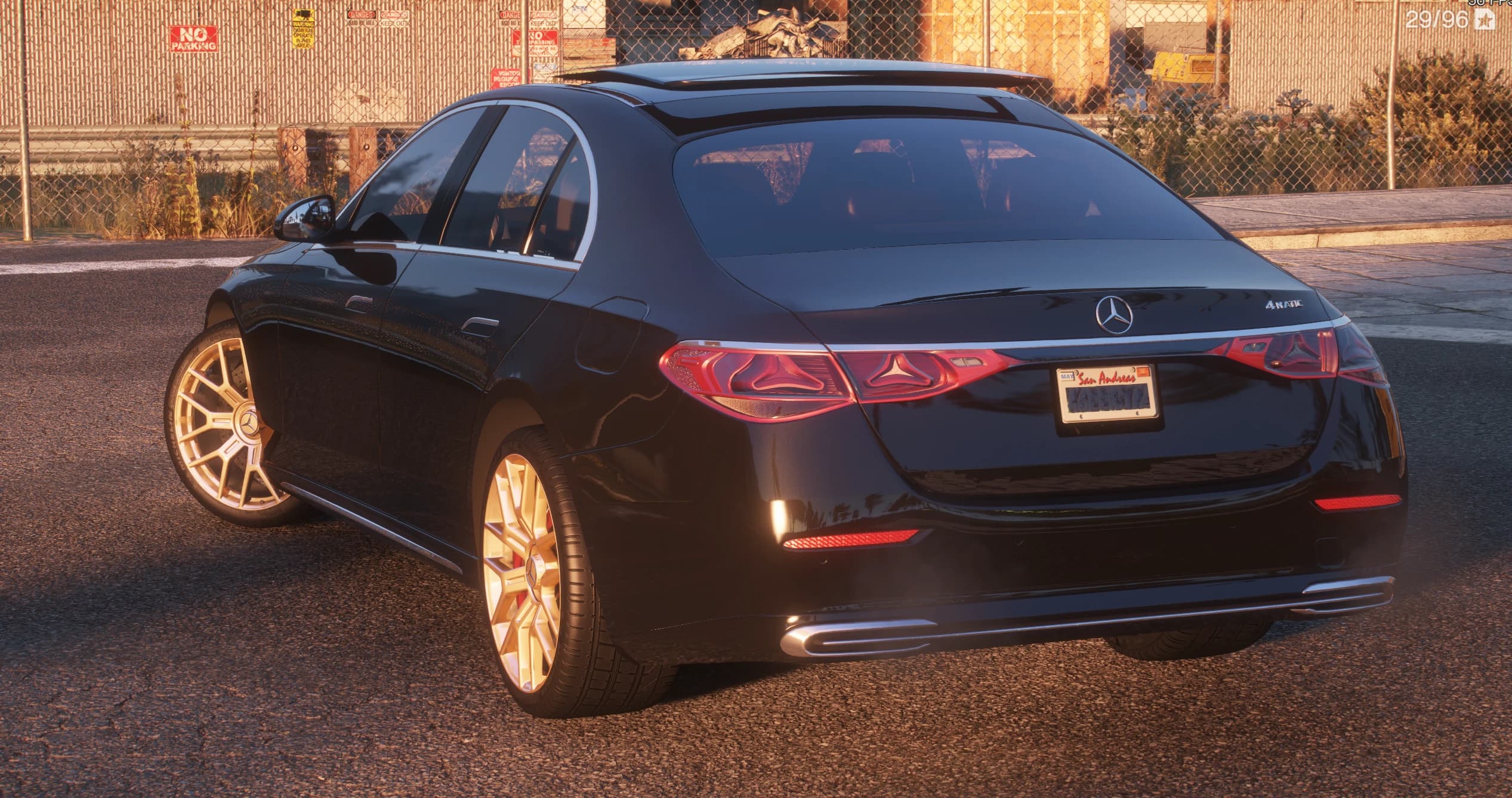 Tres cuartos trasero del E350 negro con la insignia 4MATIC, pilotos LED conectados y matrícula de San Andreas, junto a una valla metálica