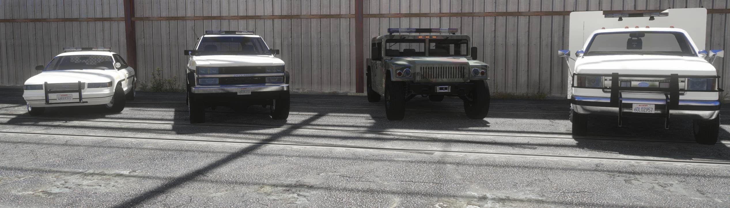 La primera fila de cuatro vehículos del sheriff — un coche patrulla, un todocamino, un Humvee de camuflaje y un camión de rescate — alineados con la librea retro del Sheriff de Blaine County