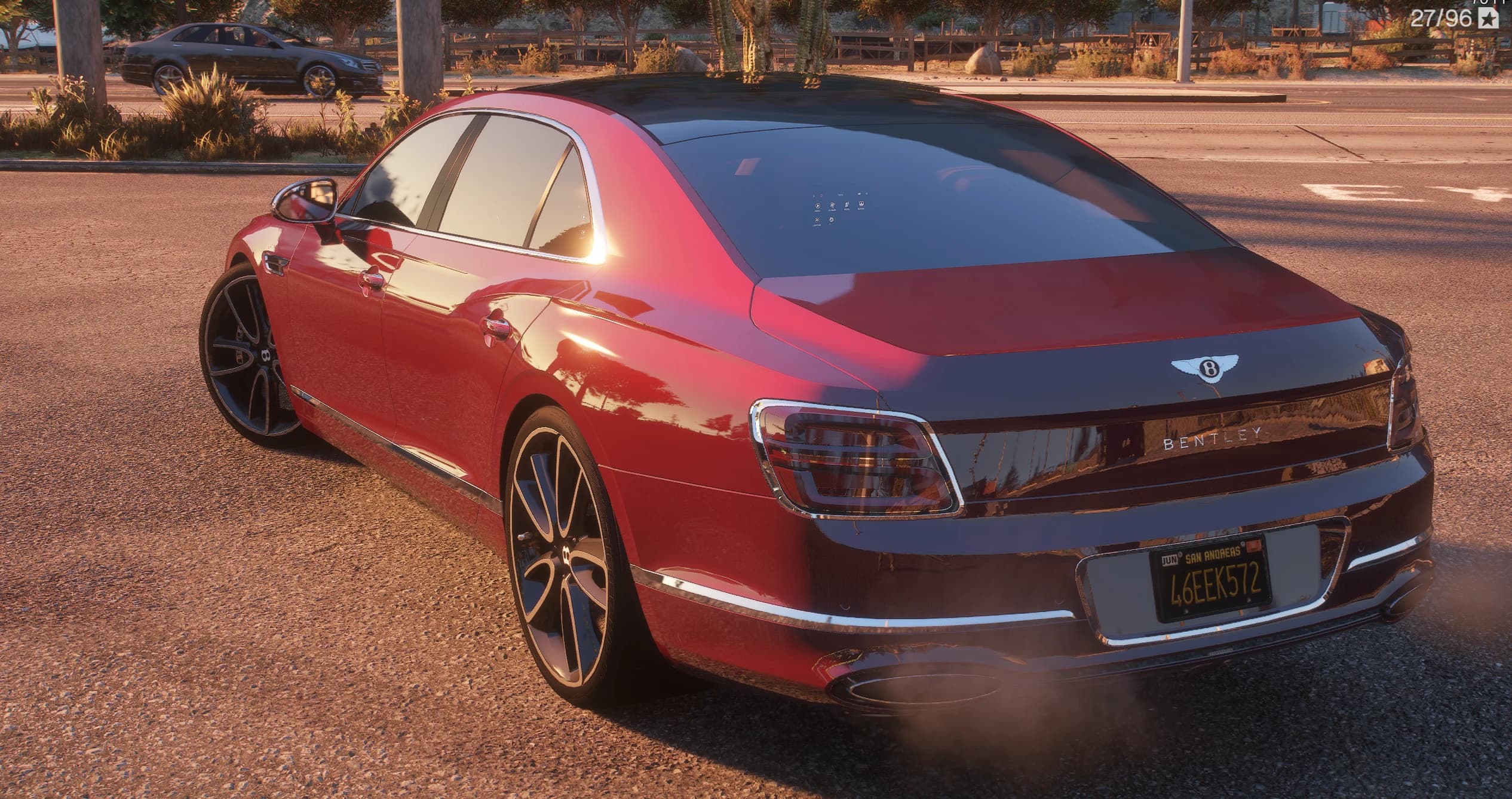 Tres cuartos trasero del Flying Spur al atardecer con el rótulo BENTLEY en la zaga, el emblema de la B alada sobre el portón, pilotos envolventes y matrícula amarilla de San Andreas 46EEK572