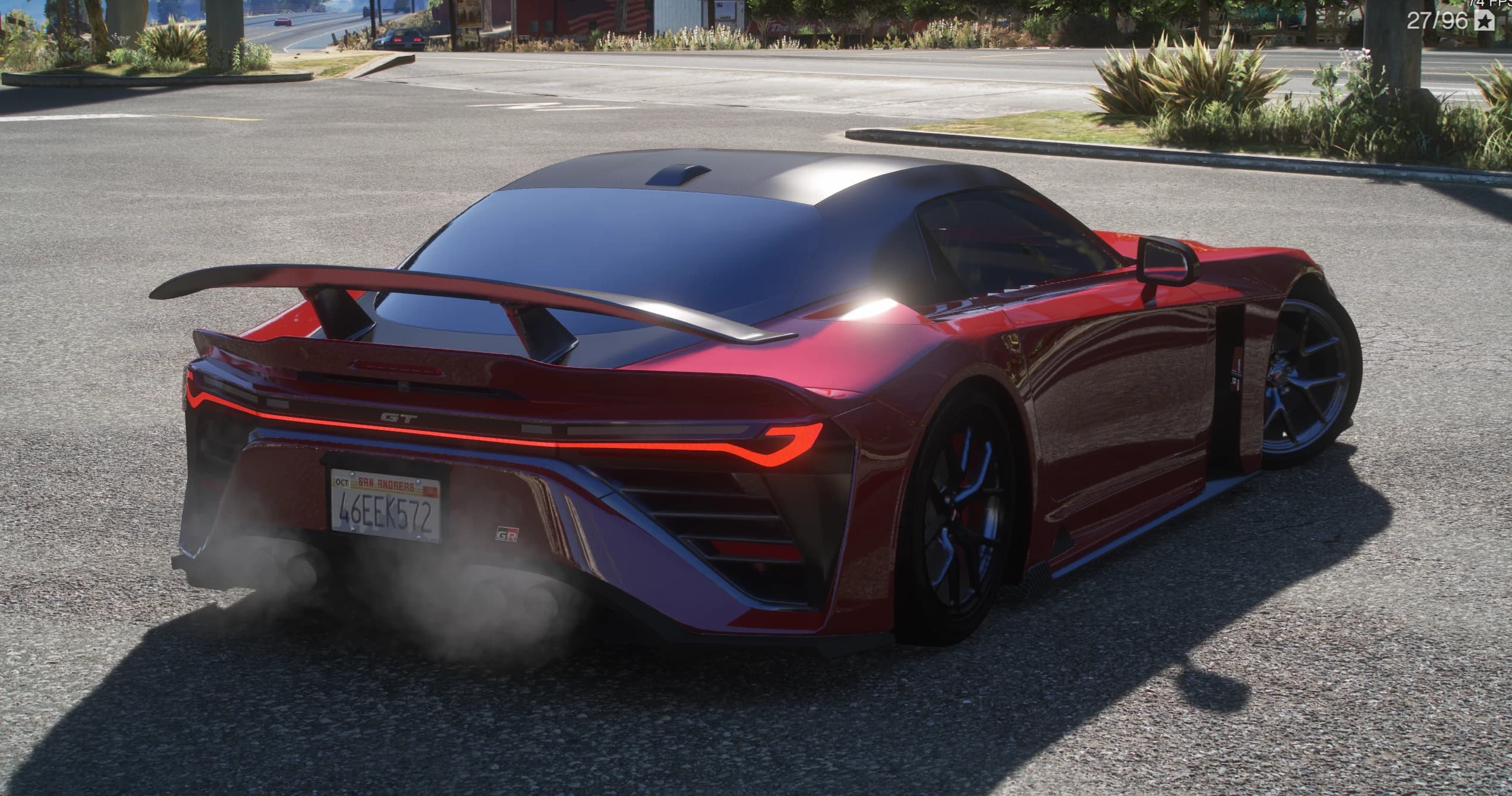 Tres cuartos trasero del GR GT rojo con la banda de luz a todo lo ancho, el emblema GT, un gran alerón trasero y escape cuádruple, en una carretera
