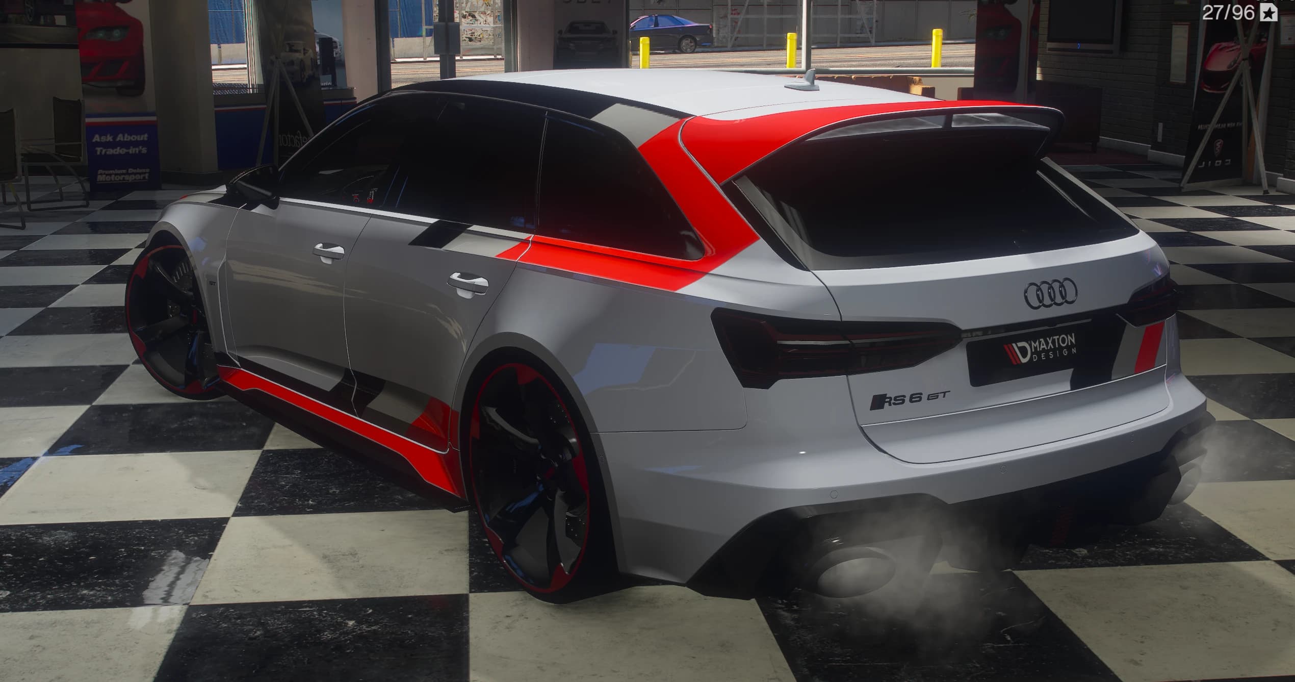 Tres cuartos trasero del RS6 GT en el concesionario: paño rojo sobre el montante trasero y el alerón de techo, emblema RS 6 GT y los cuatro aros en el portón, una placa MAXTON DESIGN en el hueco de la matrícula y los escapes ovalados soltando humo
