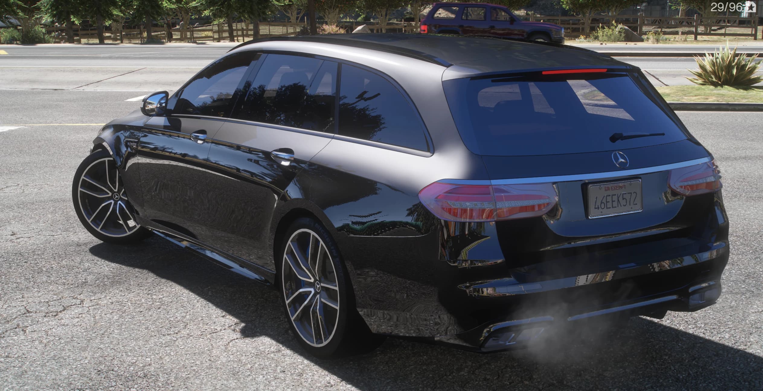 Tres cuartos trasero del familiar E63 S negro con la estrella de Mercedes, la insignia AMG, las barras de techo y el escape cuádruple