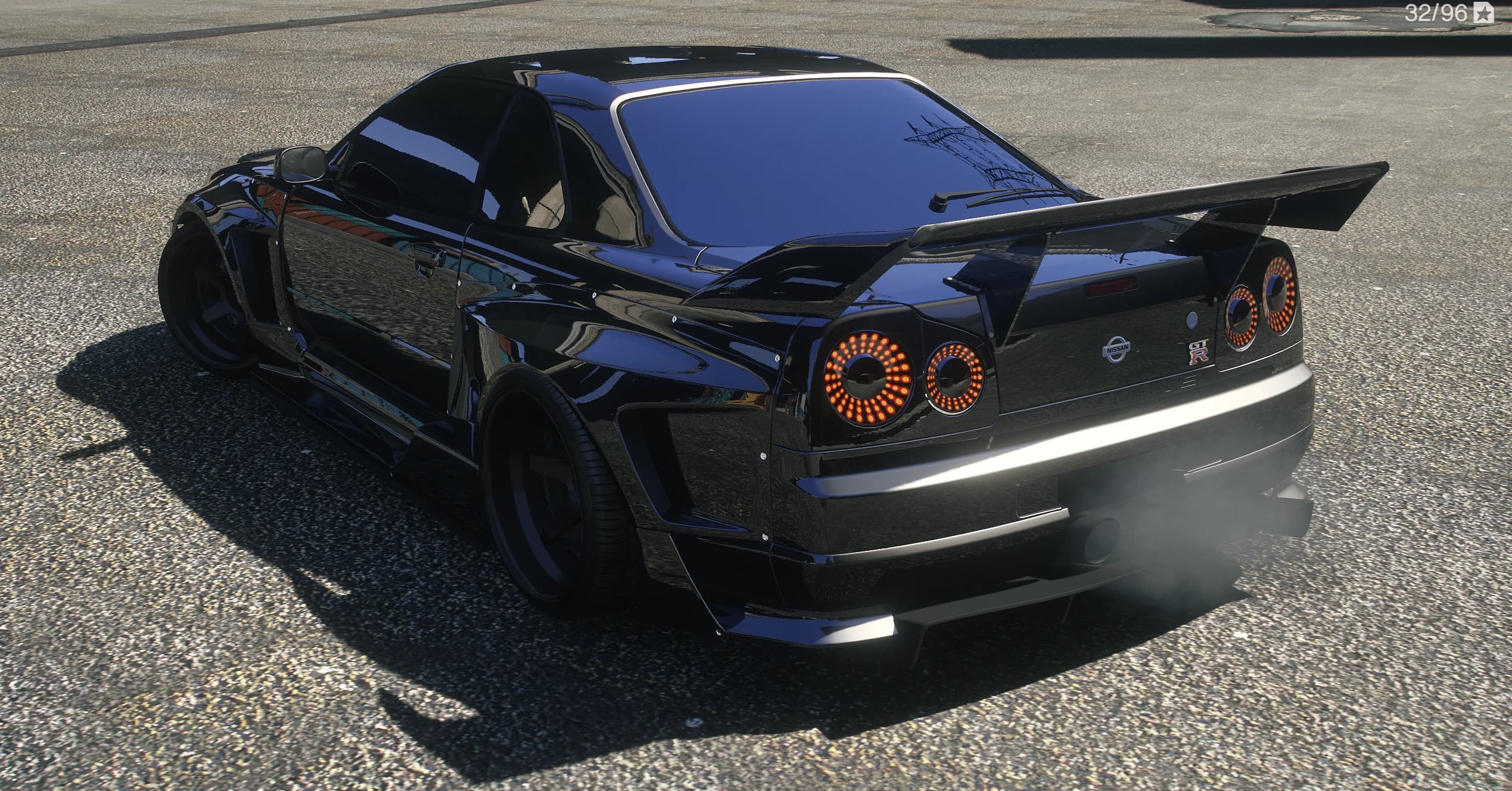 Trasera en tres cuartos del R34 GT-R negro con el gran alerón trasero y los pilotos LED redondos encendidos