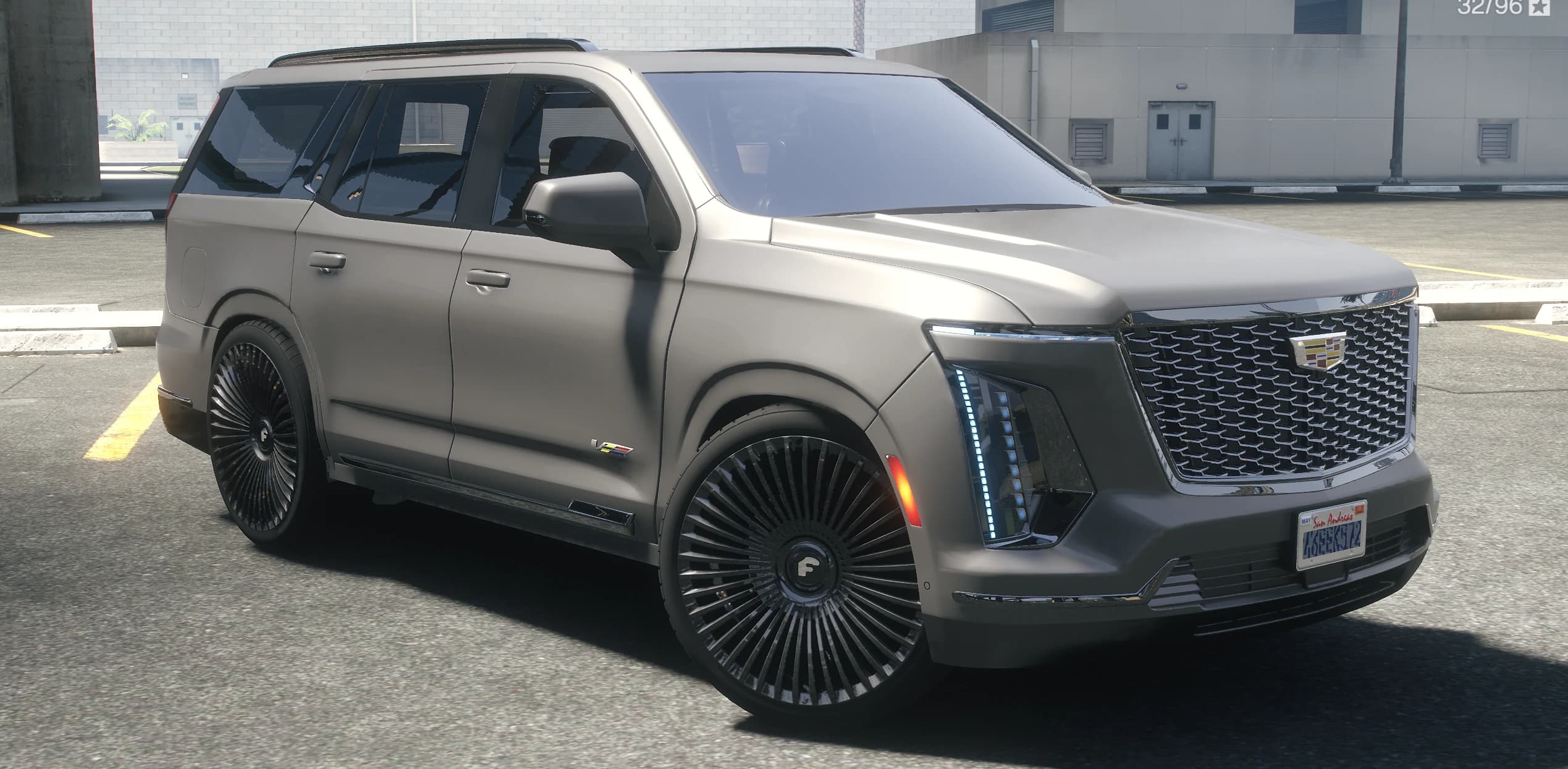 Vista frontal en tres cuartos del Escalade 2025 gris mate con la parrilla iluminada y las llantas donk altas de radios múltiples