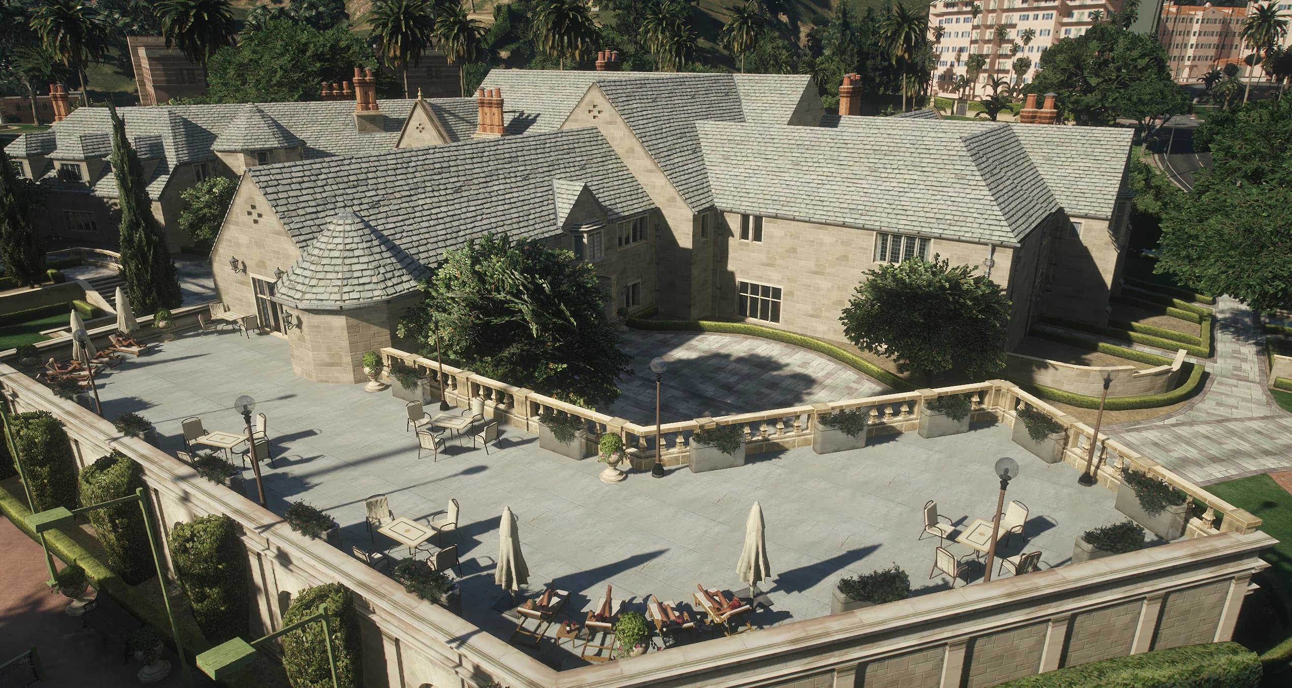 Terraza amurallada con tumbonas, mesas y sombrillas junto a la mansión