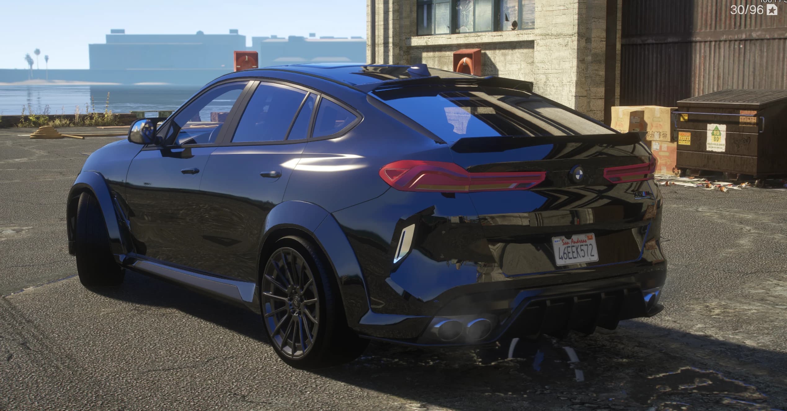 Tres cuartos trasero del X6M en un muelle, con los pasos de rueda ensanchados, el alerón tipo ducktail, los pilotos traseros conectados de lado a lado, el emblema BMW, los cuatro escapes y una matrícula de San Andreas con el texto 46EEK572
