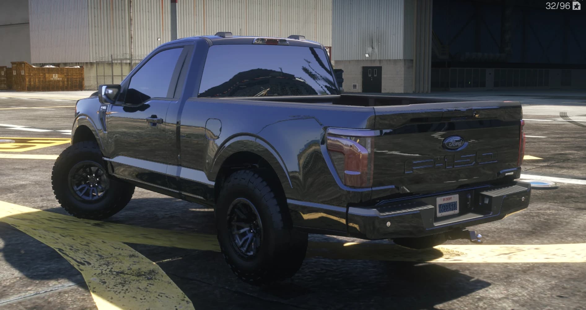 Vista trasera en tres cuartos con el portón estampado F-150, el paragolpes con bola de remolque y la postura elevada sobre neumáticos de tacos