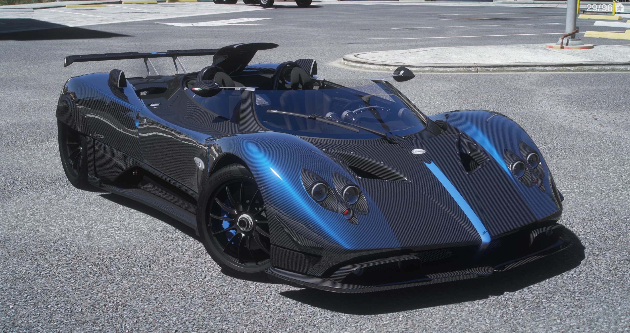 Pagani Zonda HP Barchetta en fibra de carbono con franja azul central, tres cuartos frontal, descapotable con faros redondos cuádruples, alerón alto y neumáticos Pirelli