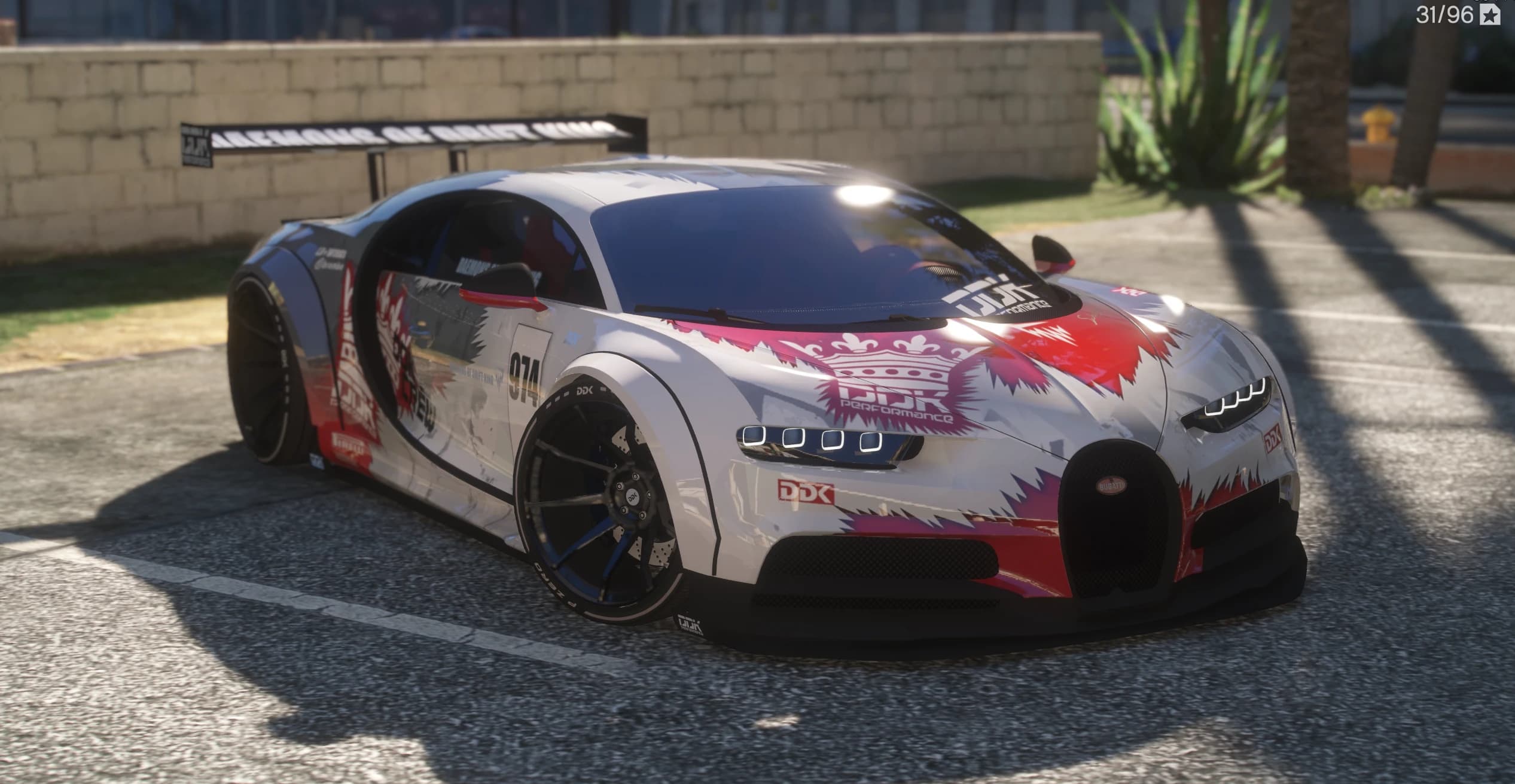 Vista frontal en tres cuartos del Bugatti Chiron ensanchado con la decoración drift DDK Performance en blanco, rojo y rosa, el dorsal 974 y un alerón GT recto sobre la zaga