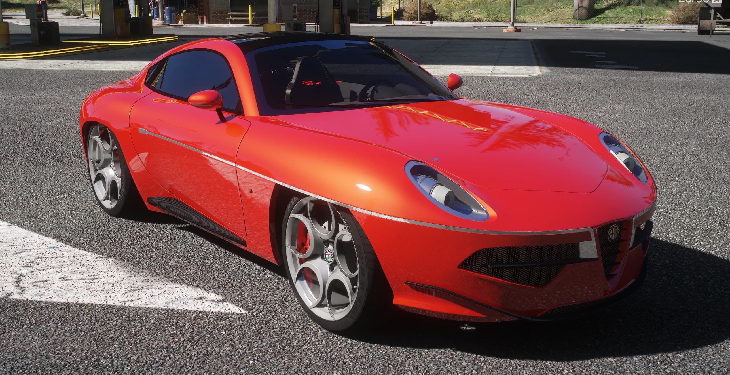Cupé Alfa Romeo Disco Volante rojo con techo negro, escudo Alfa Romeo en la parrilla y llantas plateadas de cinco huecos, tres cuartos frontal en una gasolinera