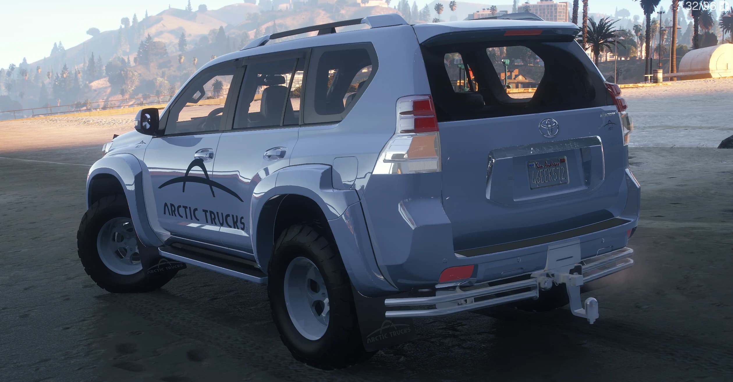 Trasera en tres cuartos del Prado con las barras de techo, la bola de remolque, los neumáticos de tacos y el emblema Land Cruiser