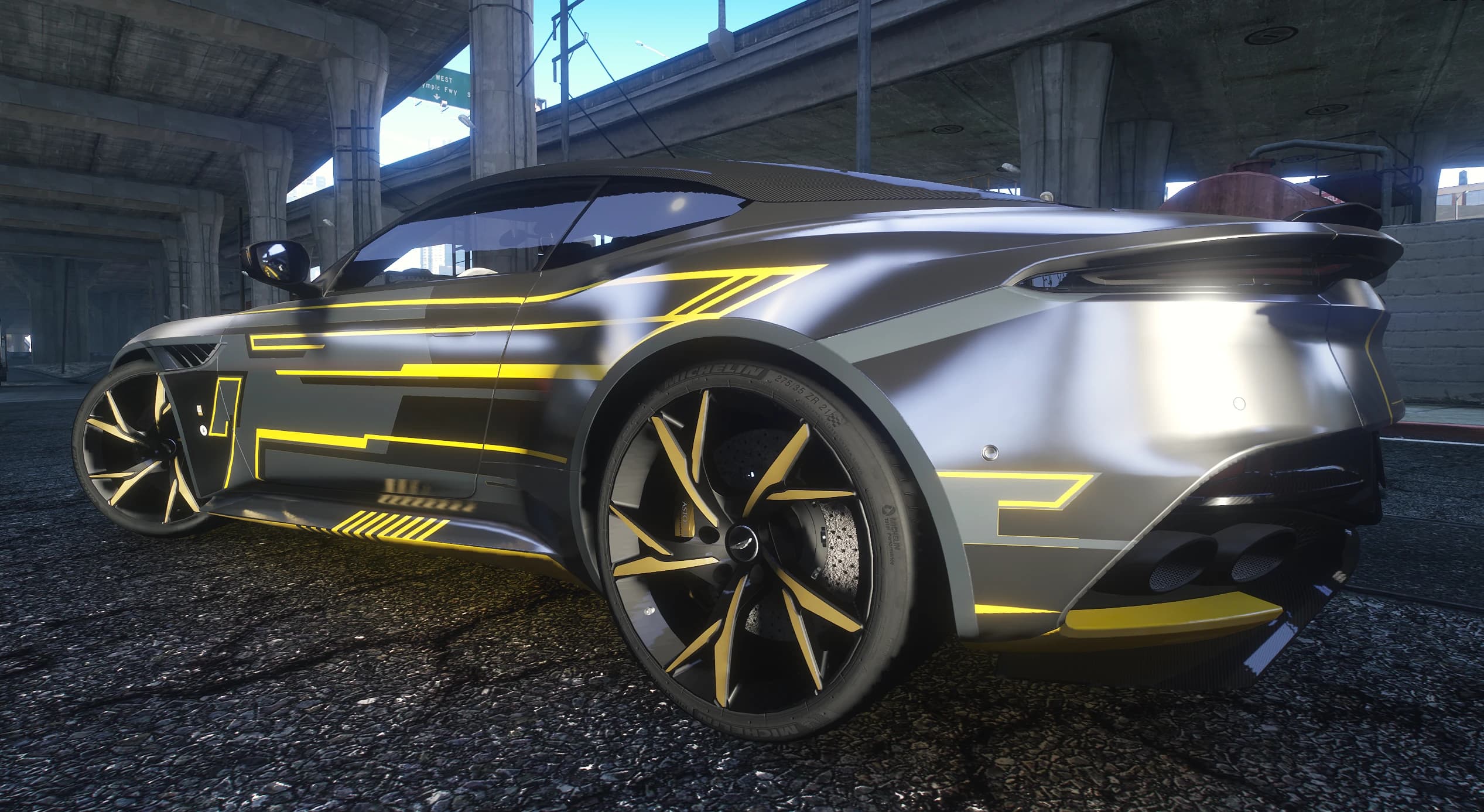 Vista lateral del DBS Superleggera gris con la decoración de líneas amarillas y llantas con detalles dorados