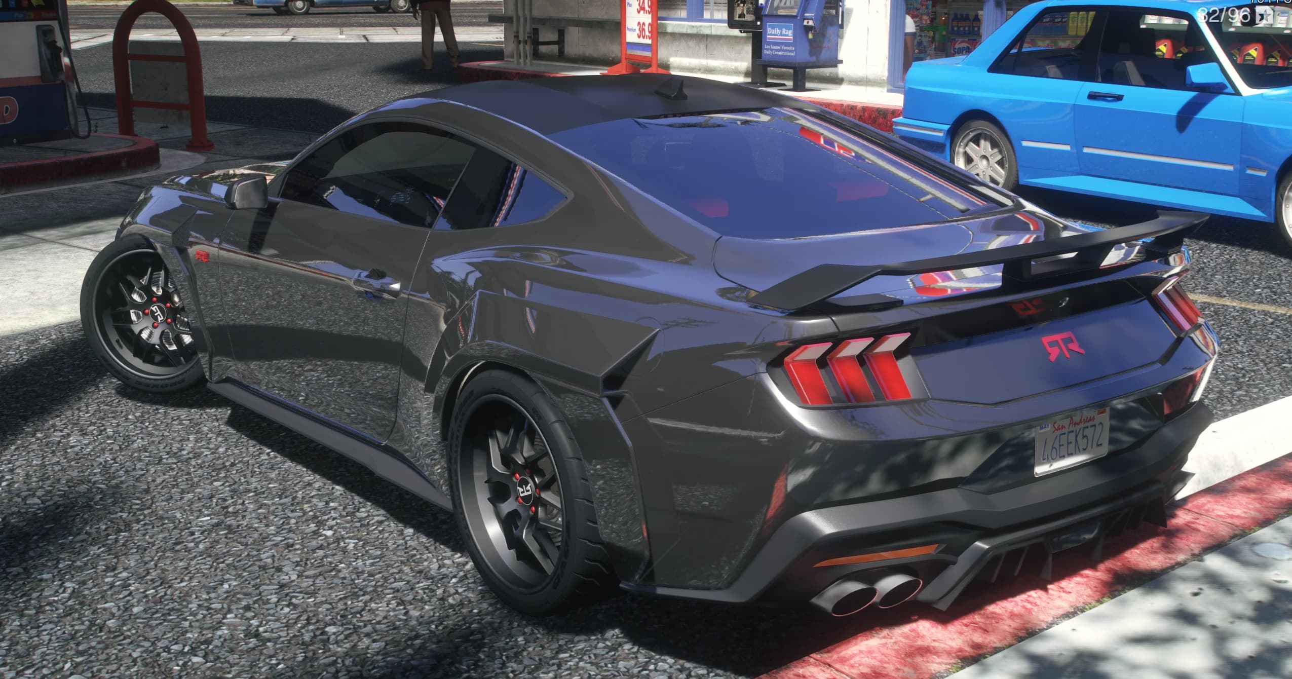 Vista trasera en tres cuartos del Mustang RTR en una gasolinera con el alerón, los pilotos en flecha y las letras RTR