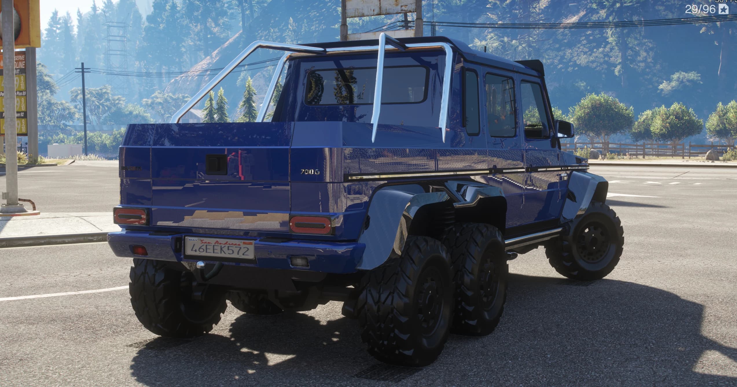 Tres cuartos trasero del G63 6x6 azul con la caja de la pickup, el emblema 700G, la barra antivuelco y los dos ejes traseros