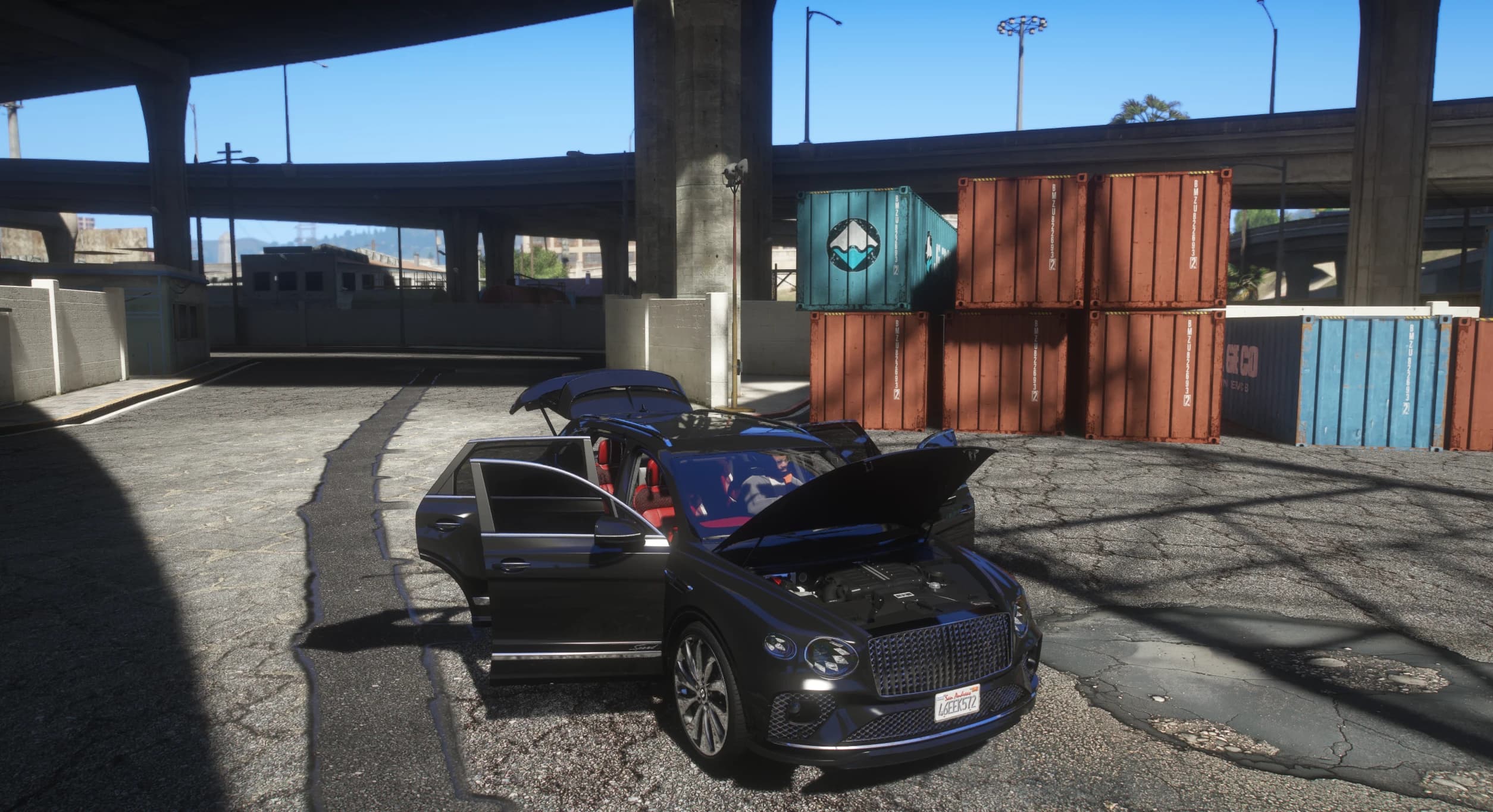 El Bentayga en un patio de contenedores con el capó, las cuatro puertas y el portón abiertos, mostrando el vano motor y la cabina roja y negra