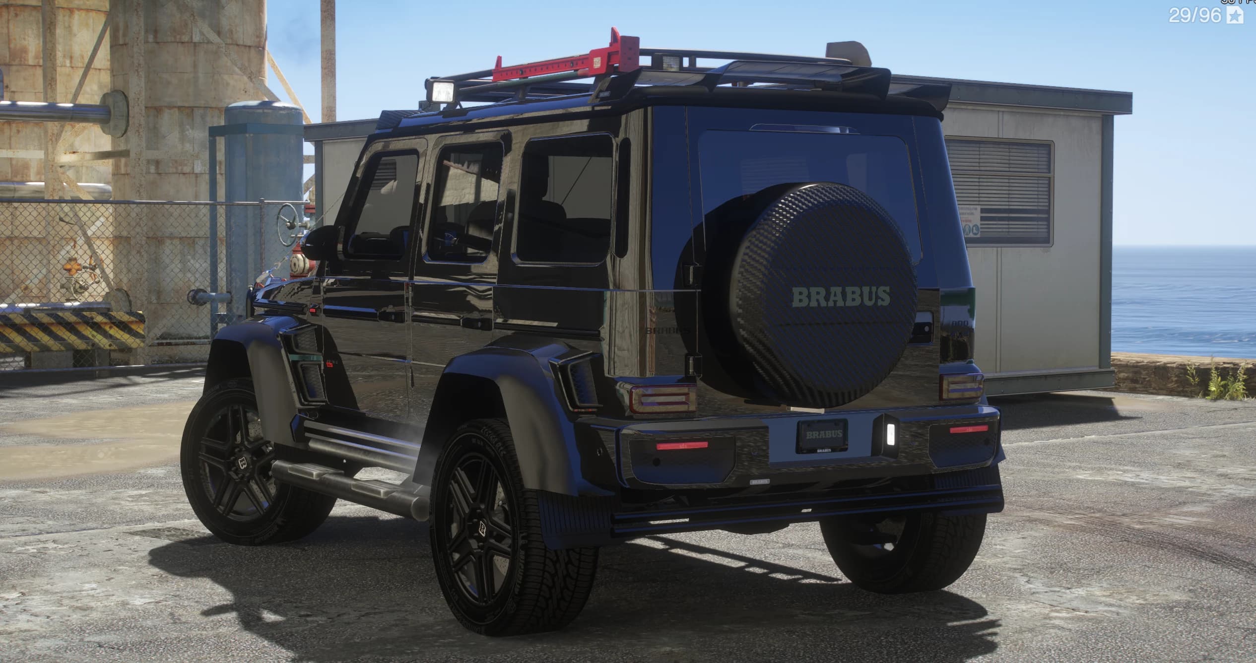 Tres cuartos trasero del G800 en un muelle, con la funda de la rueda de repuesto rotulada BRABUS y la baca de carbono con placas de tracción rojas