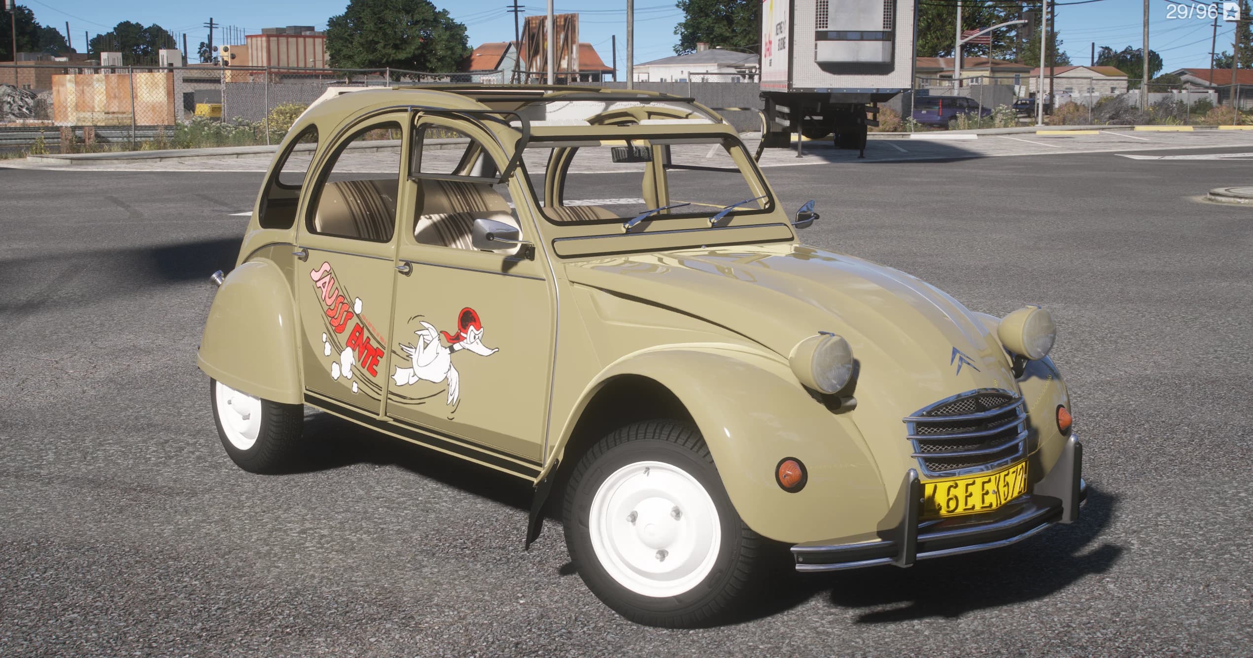 Citroën 2CV beige arena con la livery del pato de dibujos 'Saussss Ente' en la puerta y el techo de lona enrollado, en una zona industrial