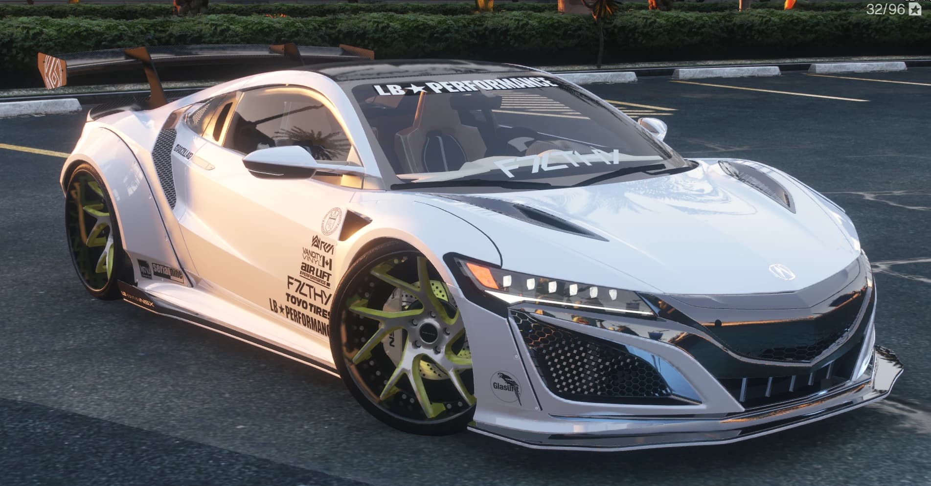 Vista frontal en tres cuartos del NSX widebody blanco con la pancarta LB Performance en el parabrisas, la columna de patrocinadores en la puerta y llantas de radios verde lima